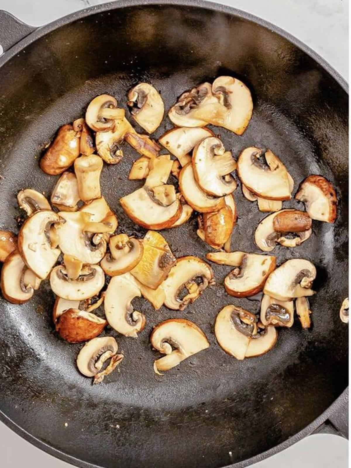 Sliced mushrooms sauteed in the skillet for Alice Springs chicken.