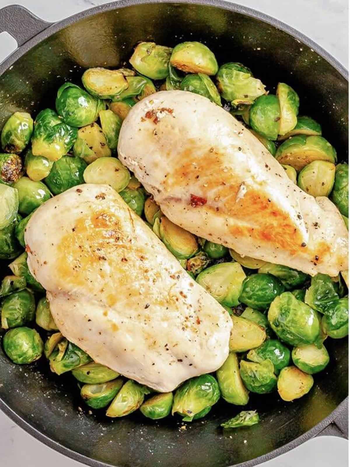 Seared chicken placed back on the Brussels sprouts to bake.