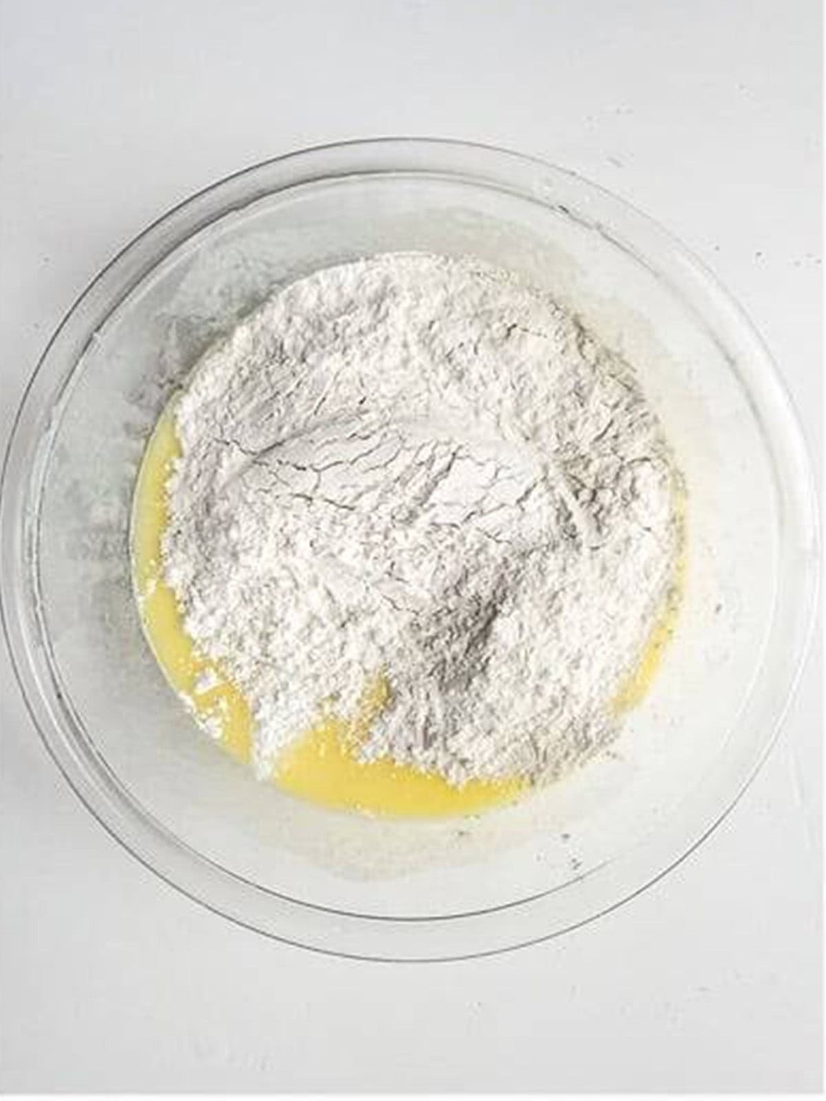 Flour and dry ingredients added to the almond cake batter bowl.