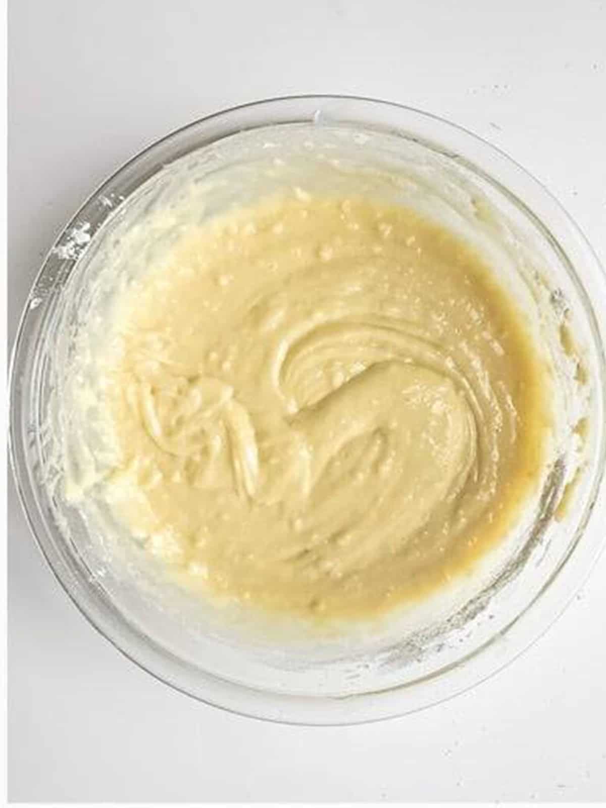 Smooth almond cake batter mixed in a glass bowl.