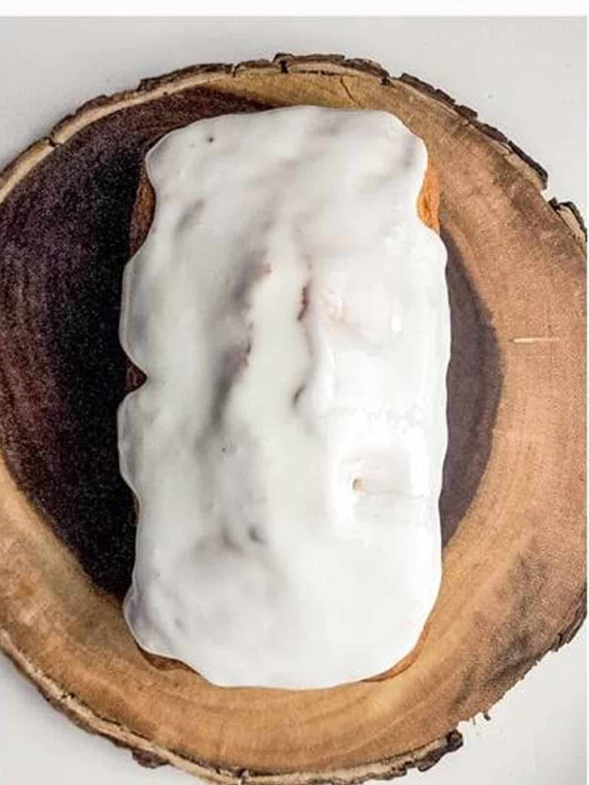 Almond loaf cake drizzled with white almond glaze on a wood board.