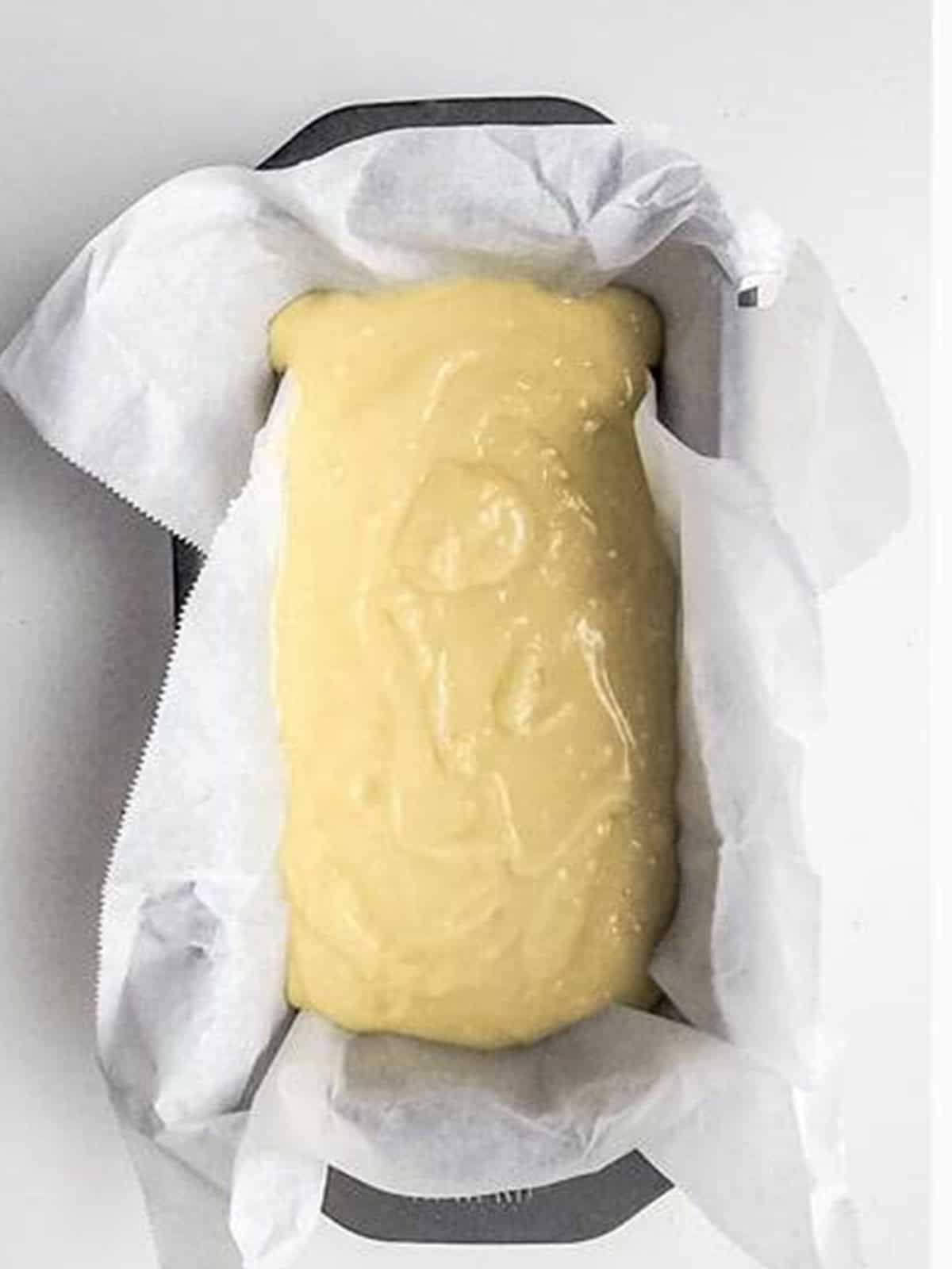 Almond cake batter poured into a parchment-lined loaf pan.