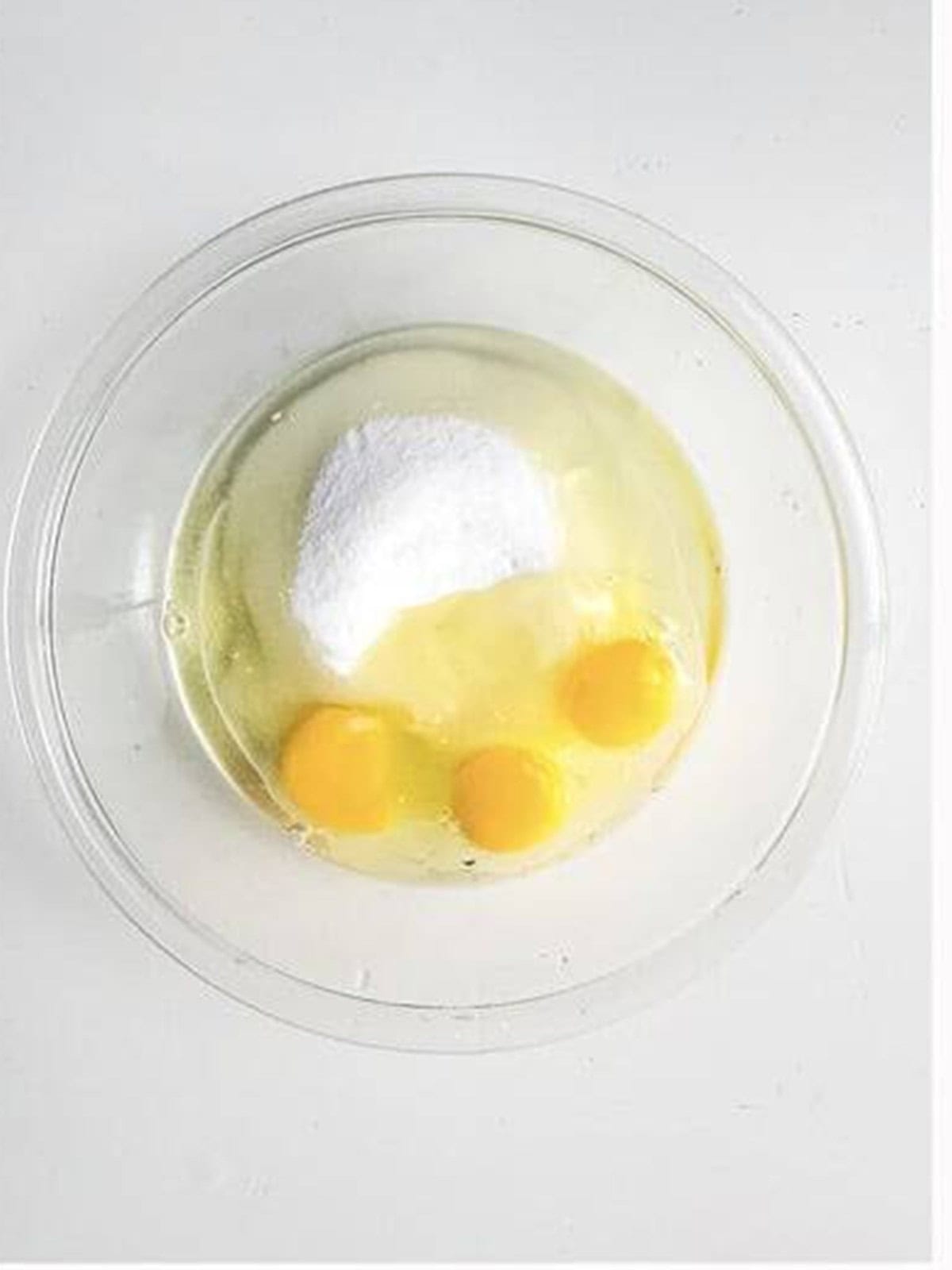 Yogurt, sugar, oil, eggs, and almond extract whisked in a bowl.
