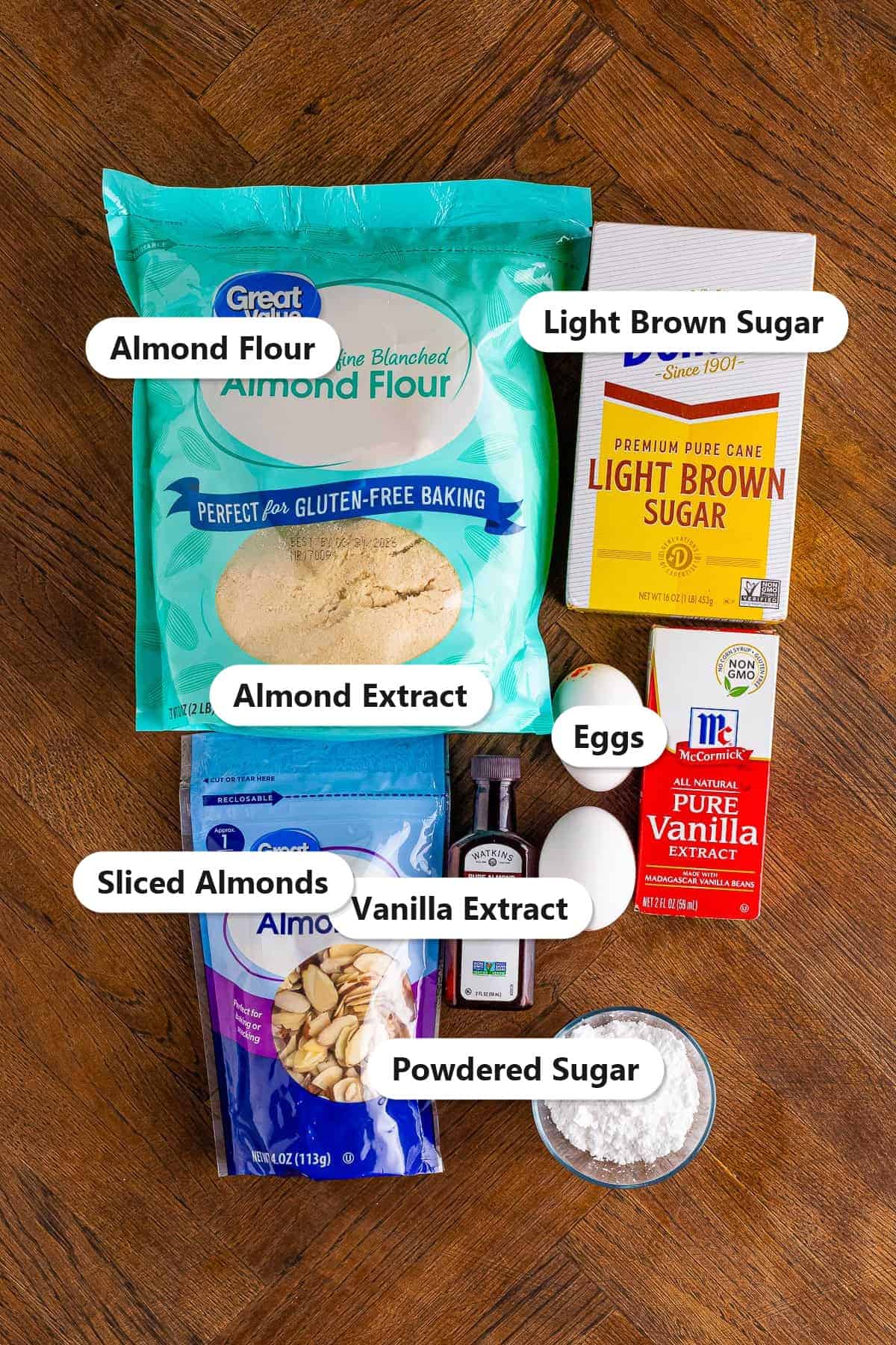 Labeled ingredients for almond flour cookies including almond flour, light brown sugar, eggs, almond extract, vanilla, sliced almonds, and powdered sugar.