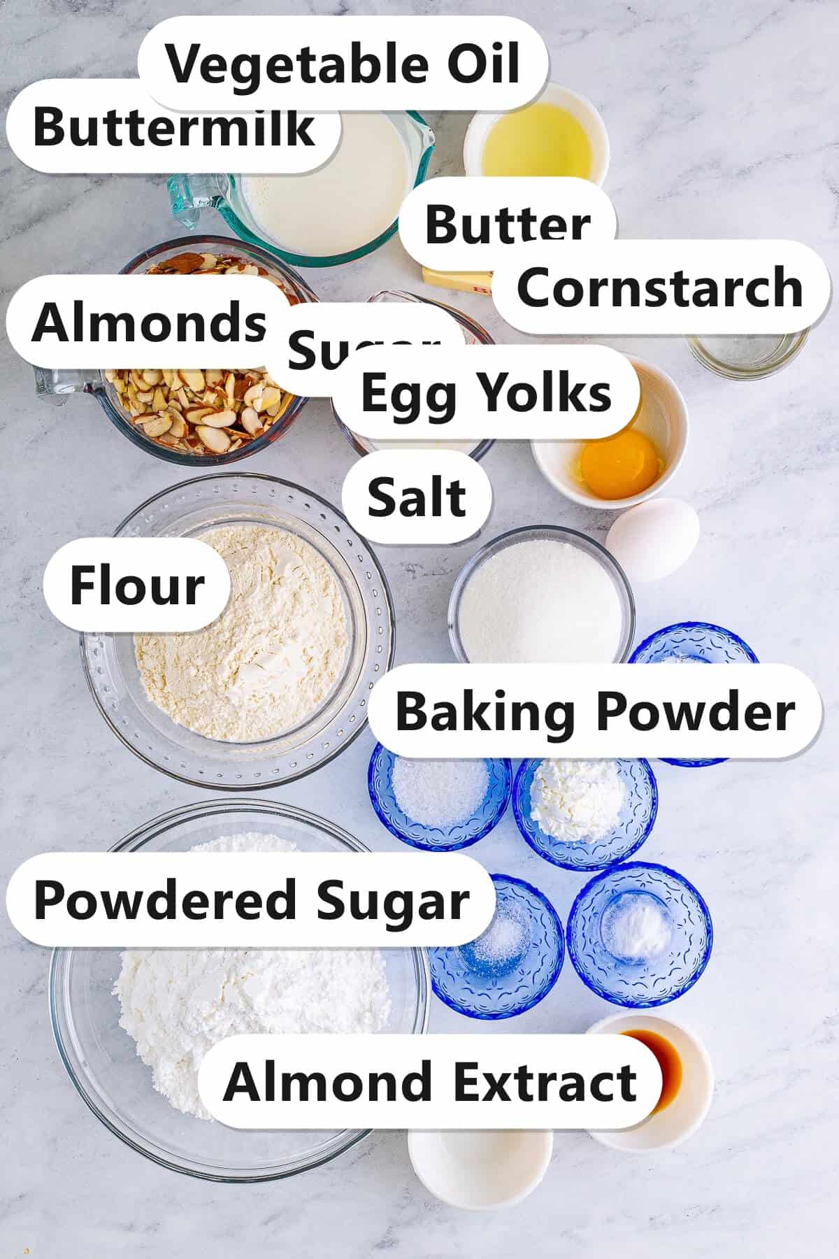 Labeled ingredients for almond torte cake including buttermilk, butter, almonds, flour, sugar, egg yolks, powdered sugar, and almond extract.