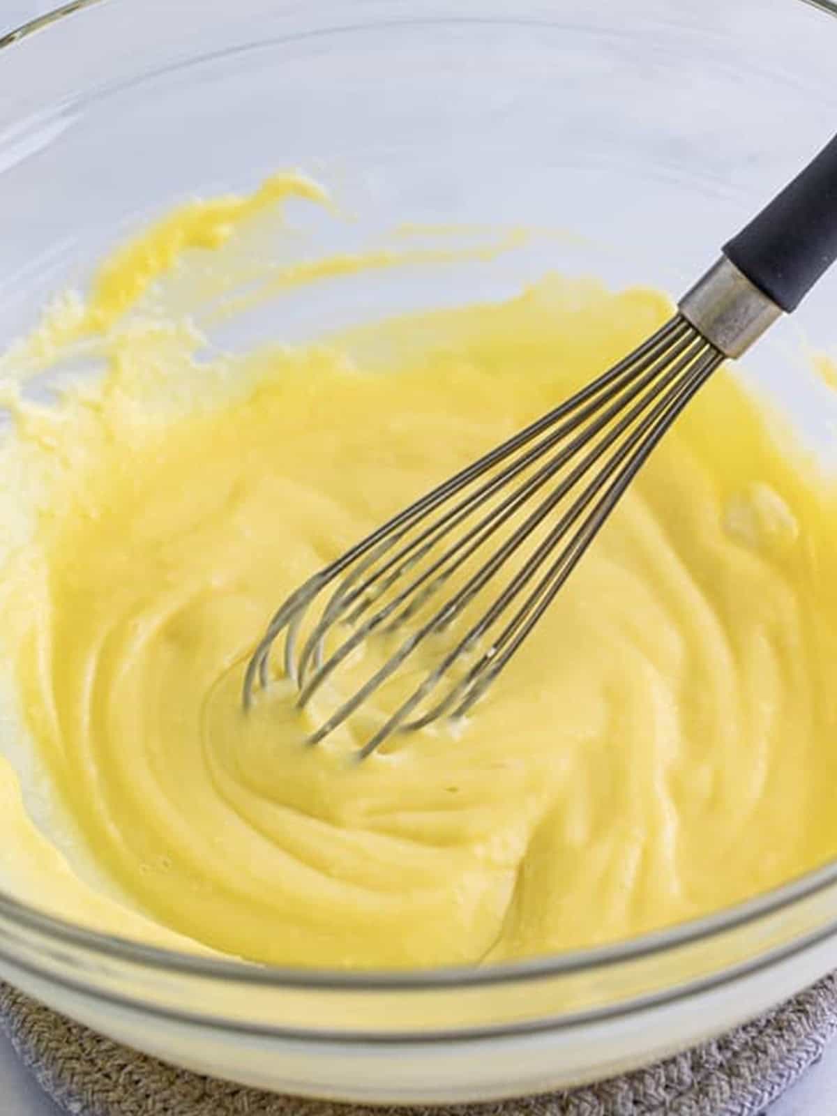 Smooth almond custard filling whisked in a glass bowl for almond torte cake.