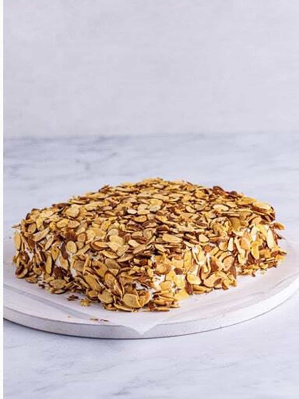 Assembled burnt almond torte cake covered in toasted sliced almonds.