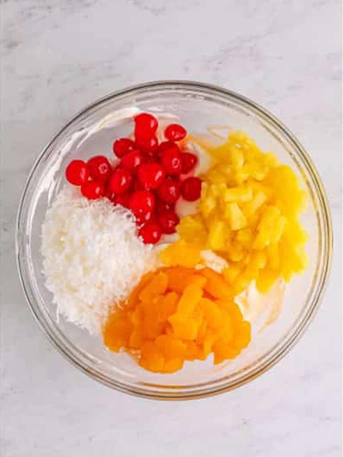 Pineapple, mandarin oranges, cherries, and coconut added to the creamy base for ambrosia salad.