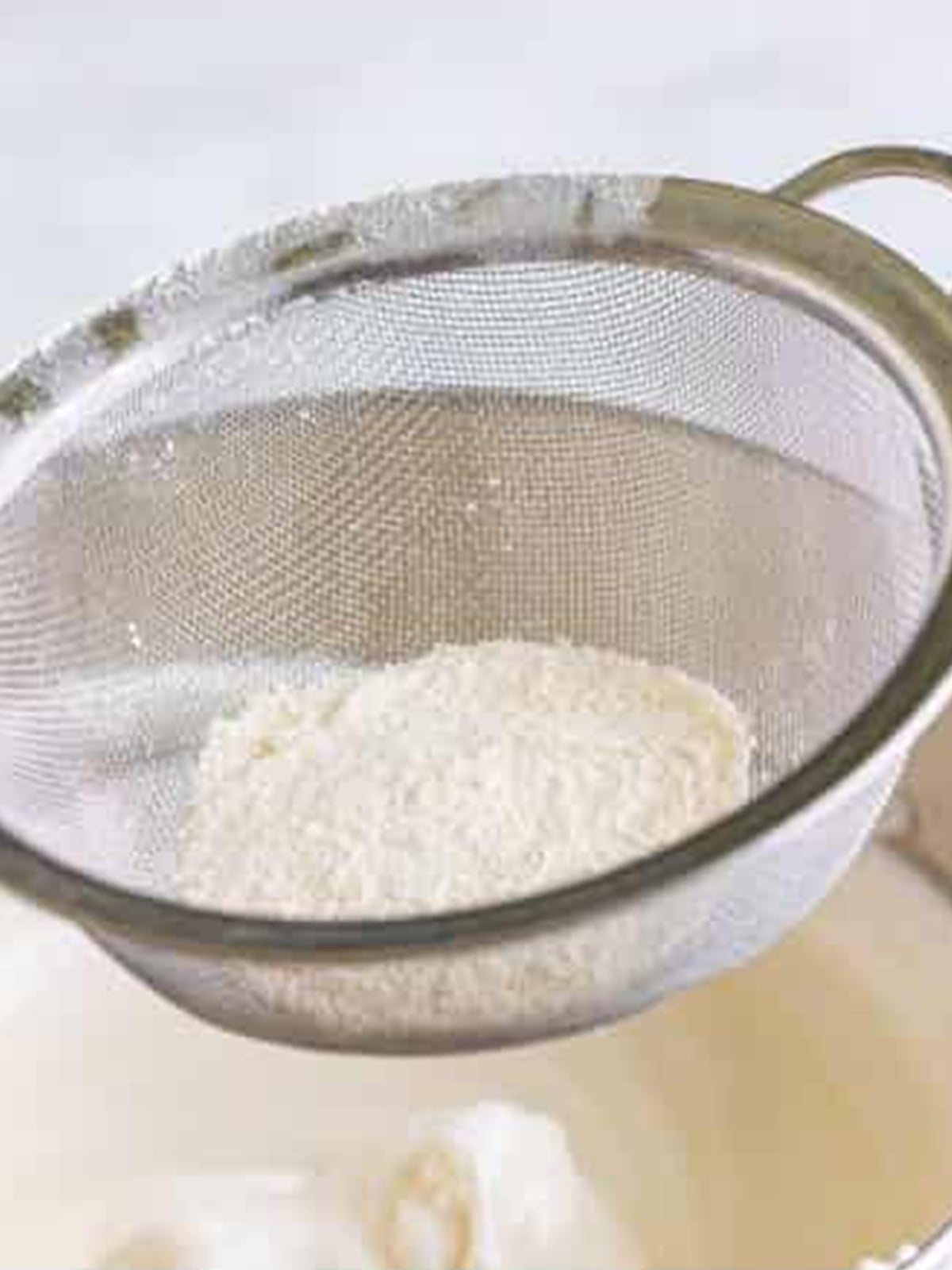 Sifting the flour mixture over whipped egg whites and gently folding it in for angel food cake.