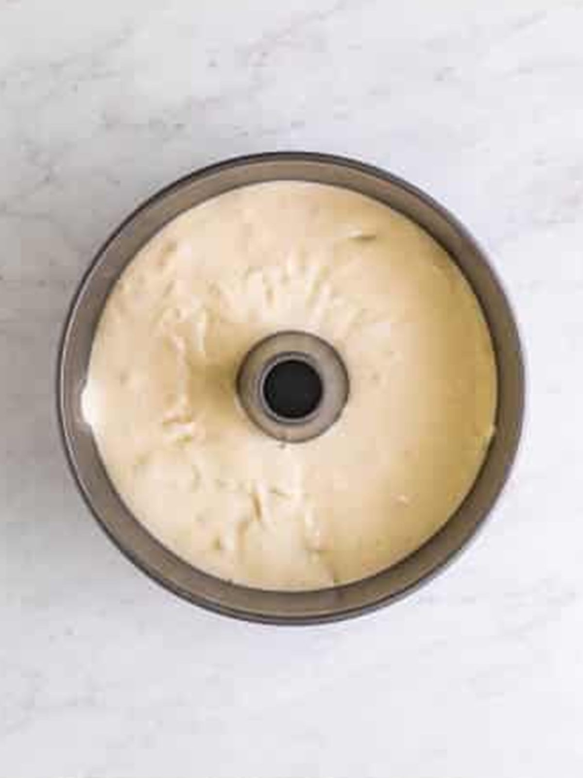 Angel food cake batter spread into an ungreased tube pan ready to bake.