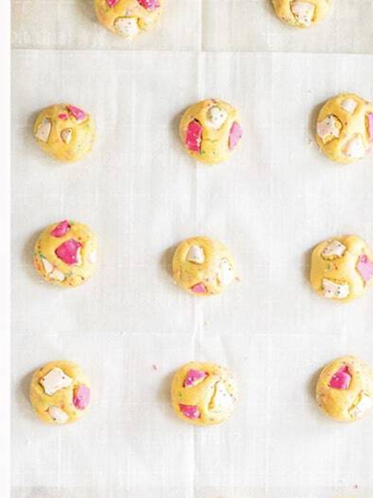 Scooped animal cracker cookie dough balls on a parchment lined tray ready to bake.