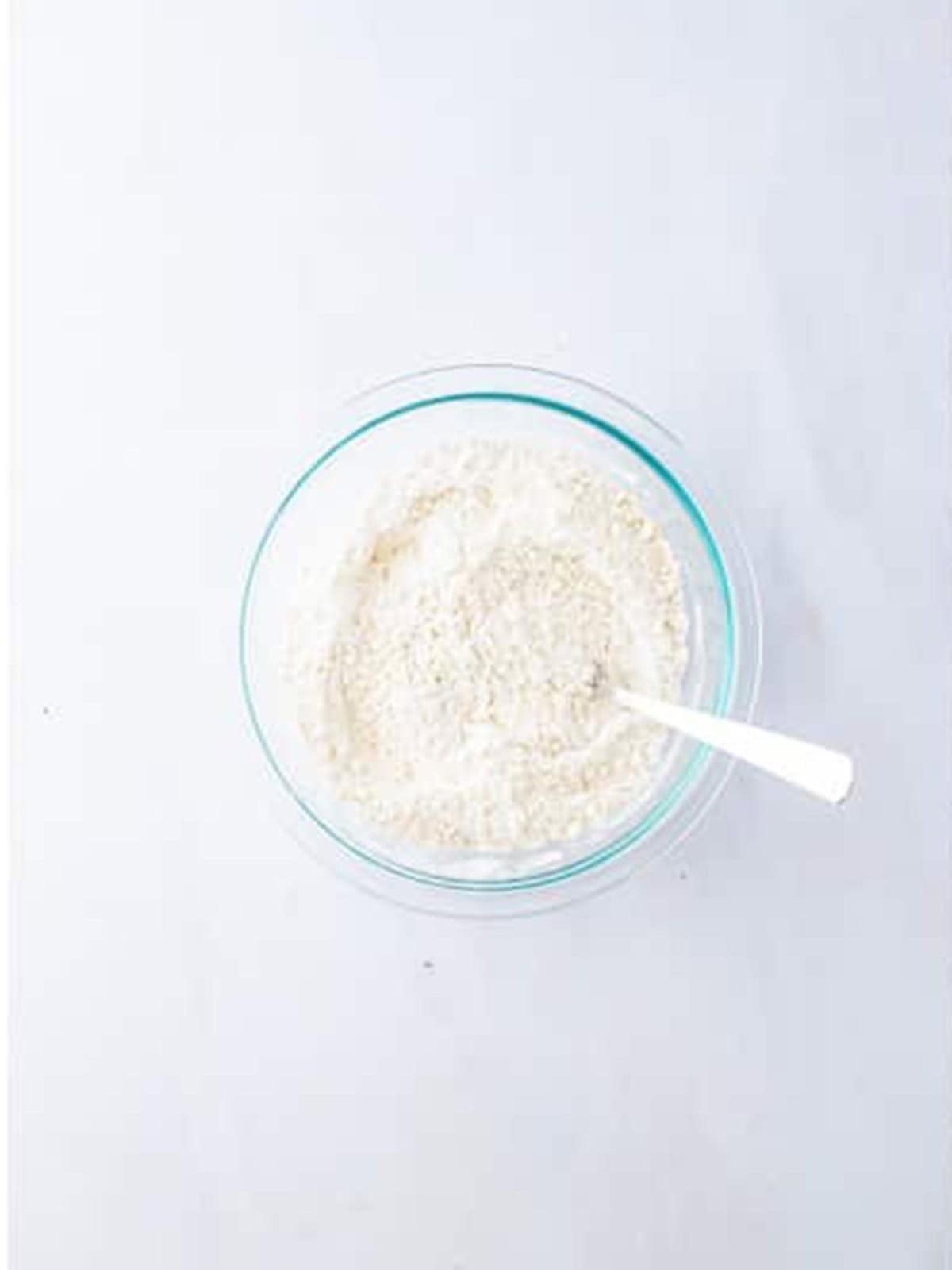 Dry ingredients mixed together in a glass bowl for apple banana muffins.