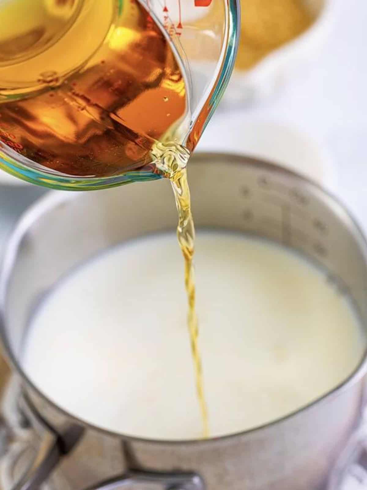 Fireball whiskey being poured into a saucepan of milk for the bread pudding custard.