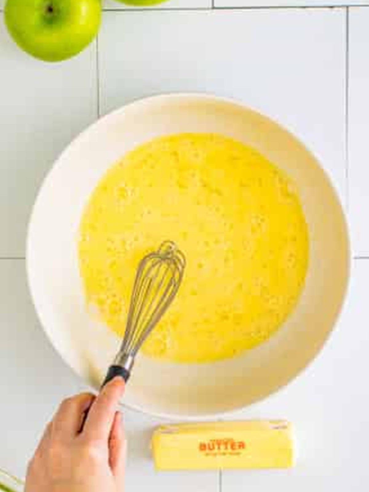 Wet ingredients whisked smooth in a bowl for apple fritter batter.
