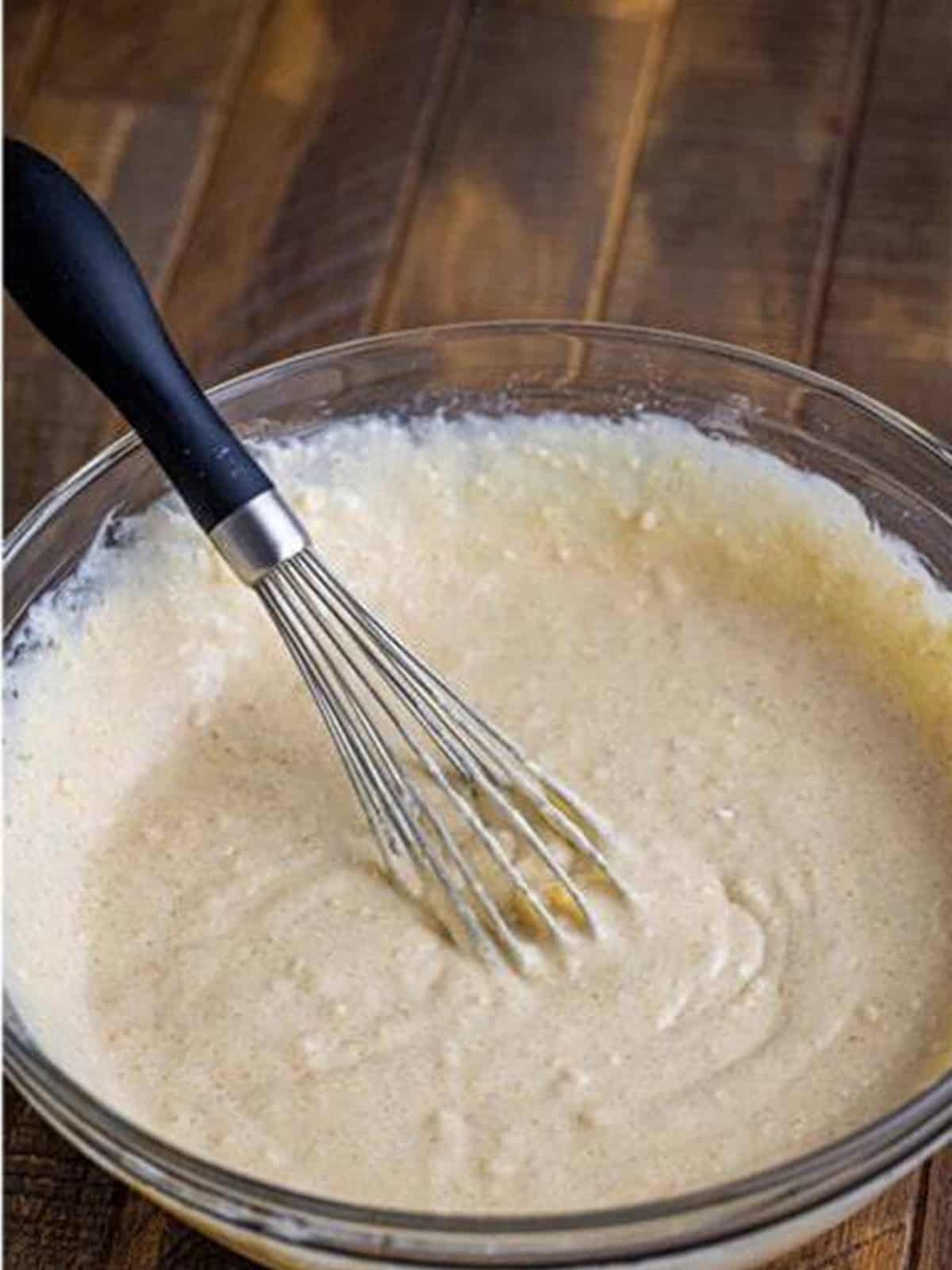 Fluffy cinnamon pancake batter whisked together in a bowl.