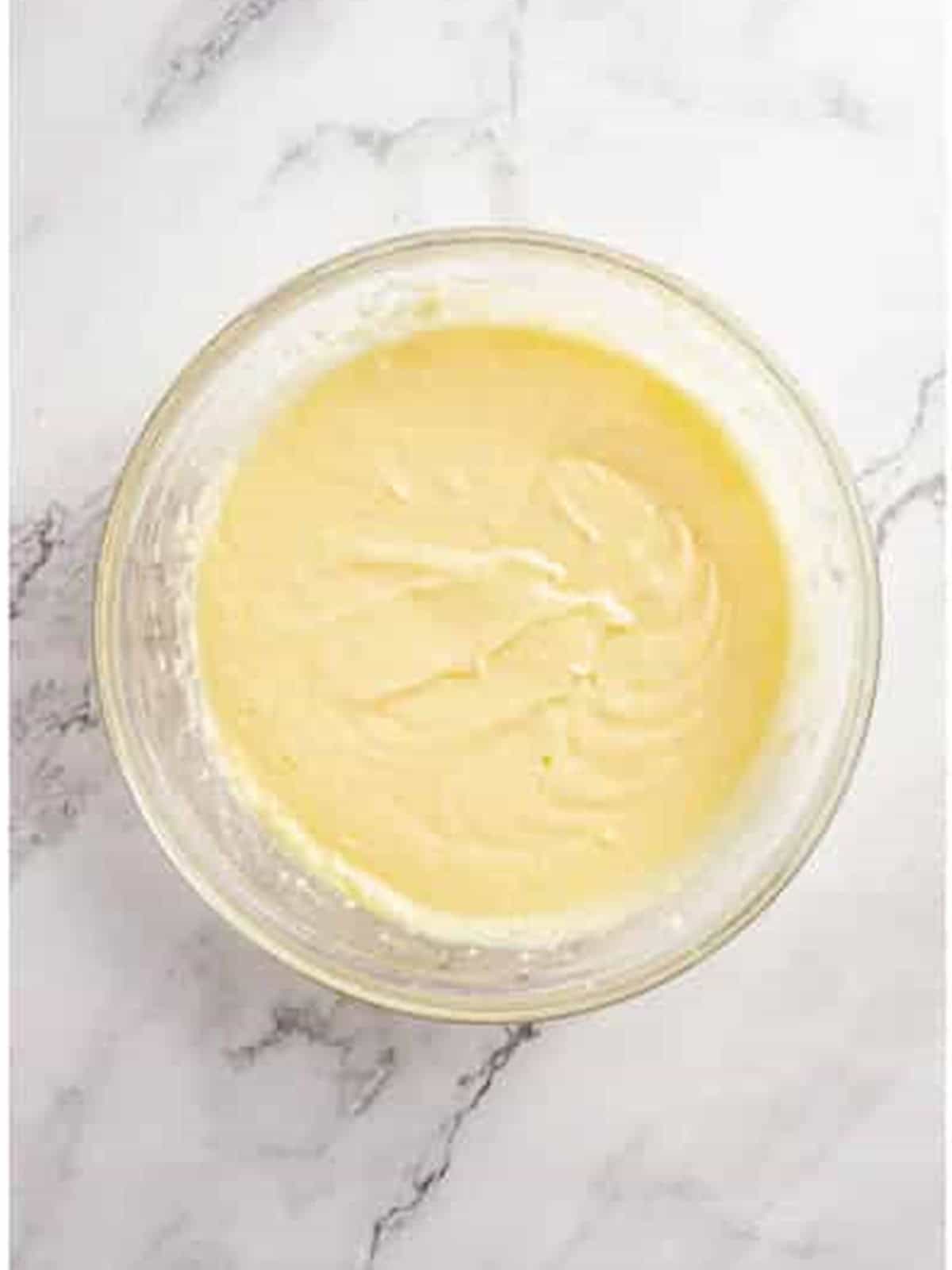 Creaming butter, sugar, and eggs in a glass bowl for apple pie bars batter.