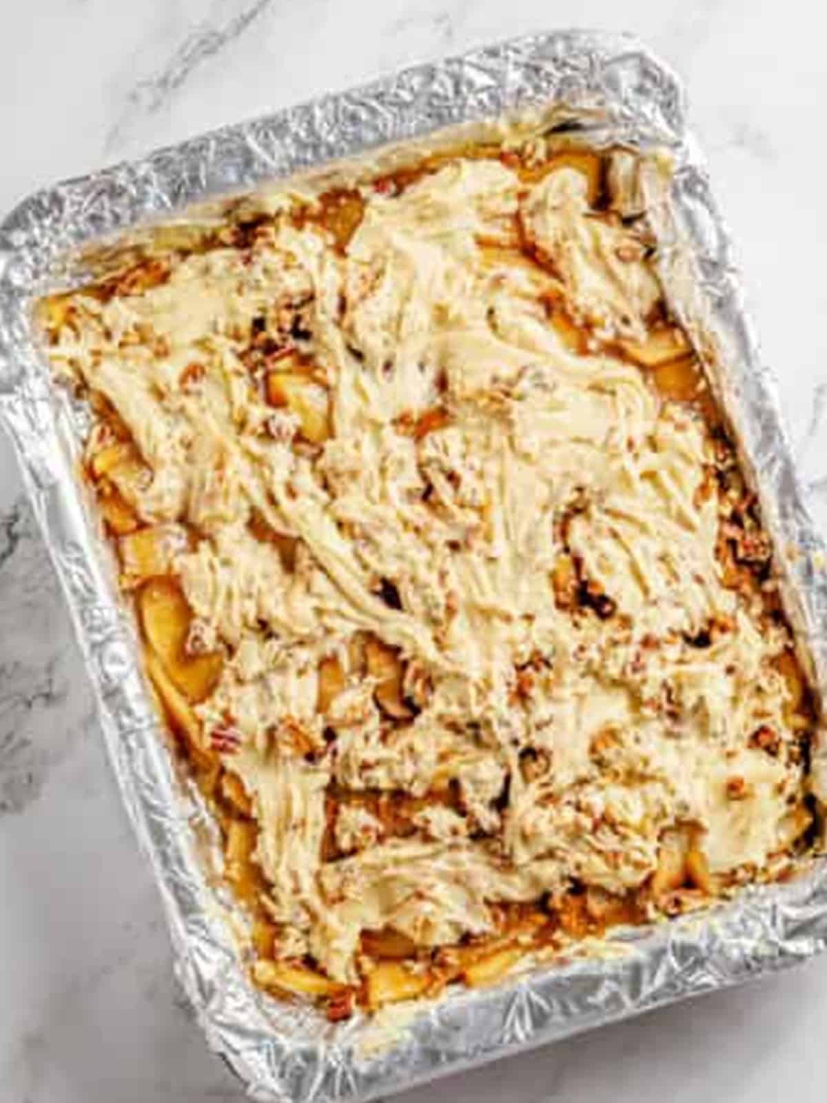 Spooning the remaining batter over the apple pie filling layer.