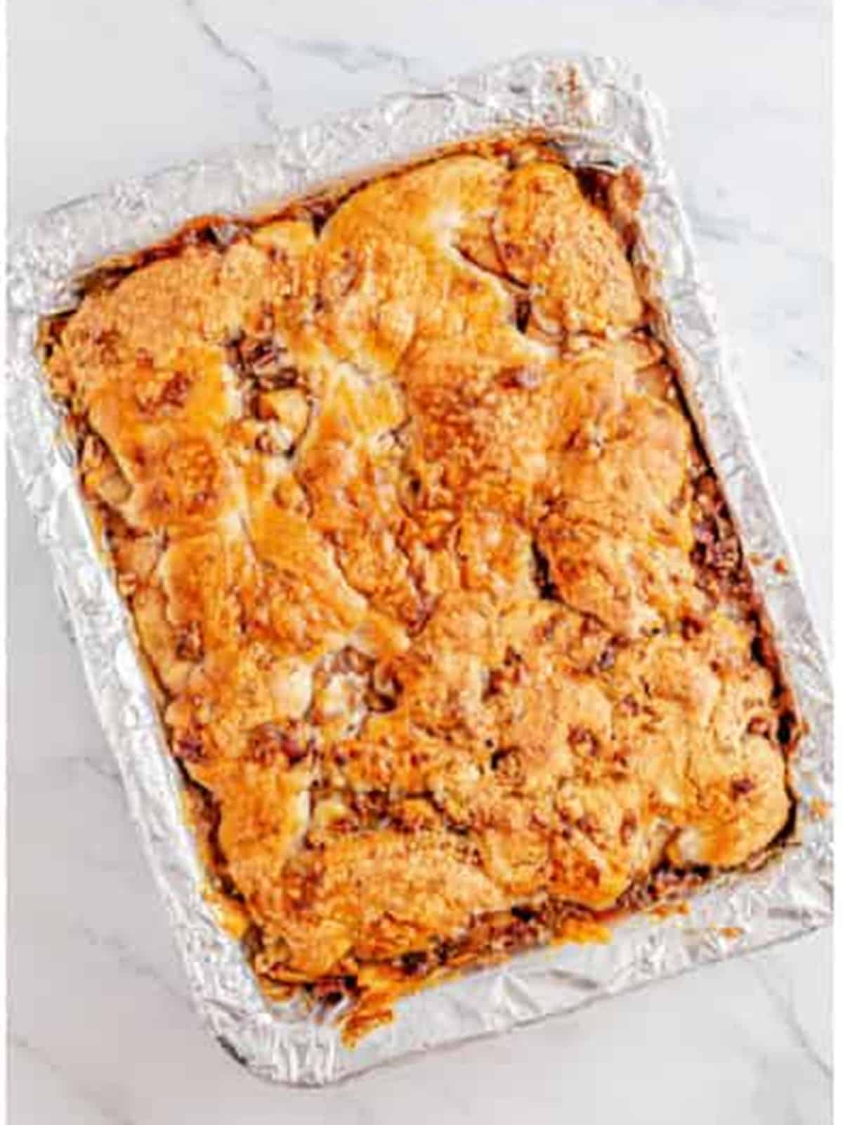 Golden baked apple pie bars fresh from the oven in a foil lined pan.