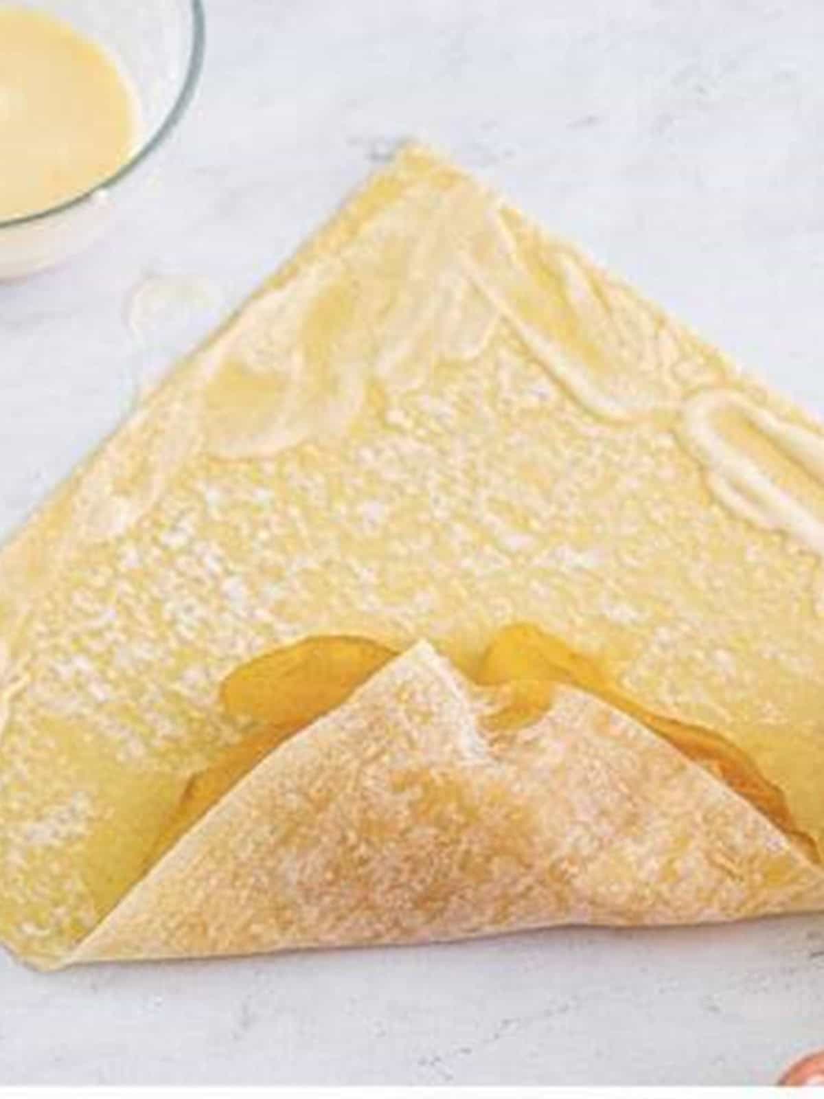 Folding the wrapper corner over the apple pie filling for apple pie egg rolls.