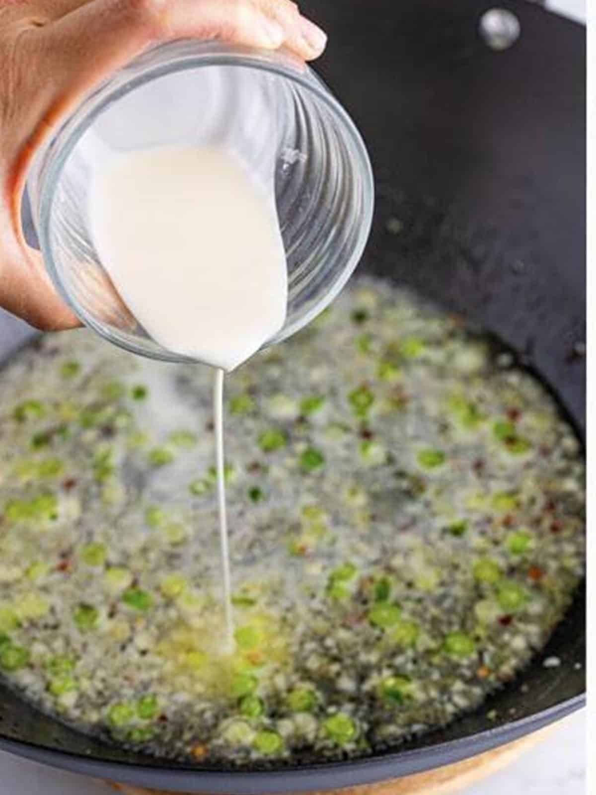 Streaming a cornstarch slurry into the simmering lemon sauce while whisking.