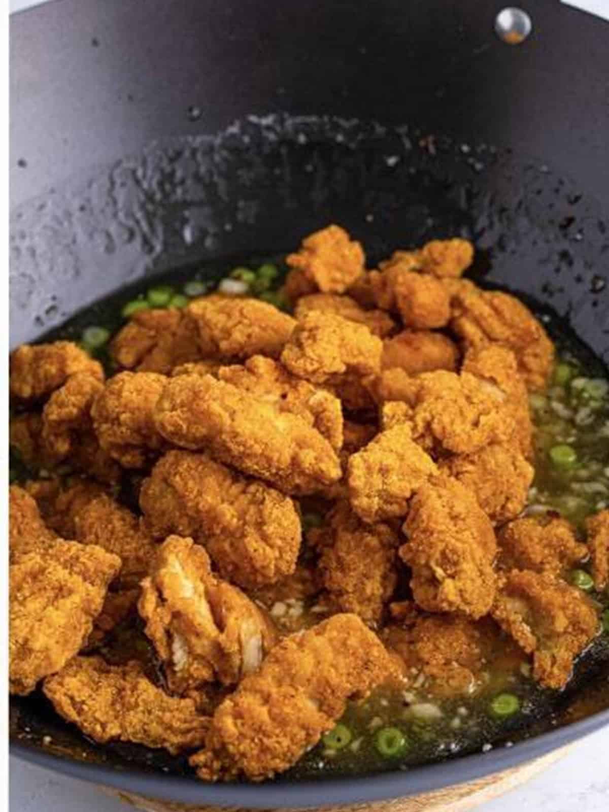 Tossing crispy popcorn chicken in the sticky asian lemon sauce.