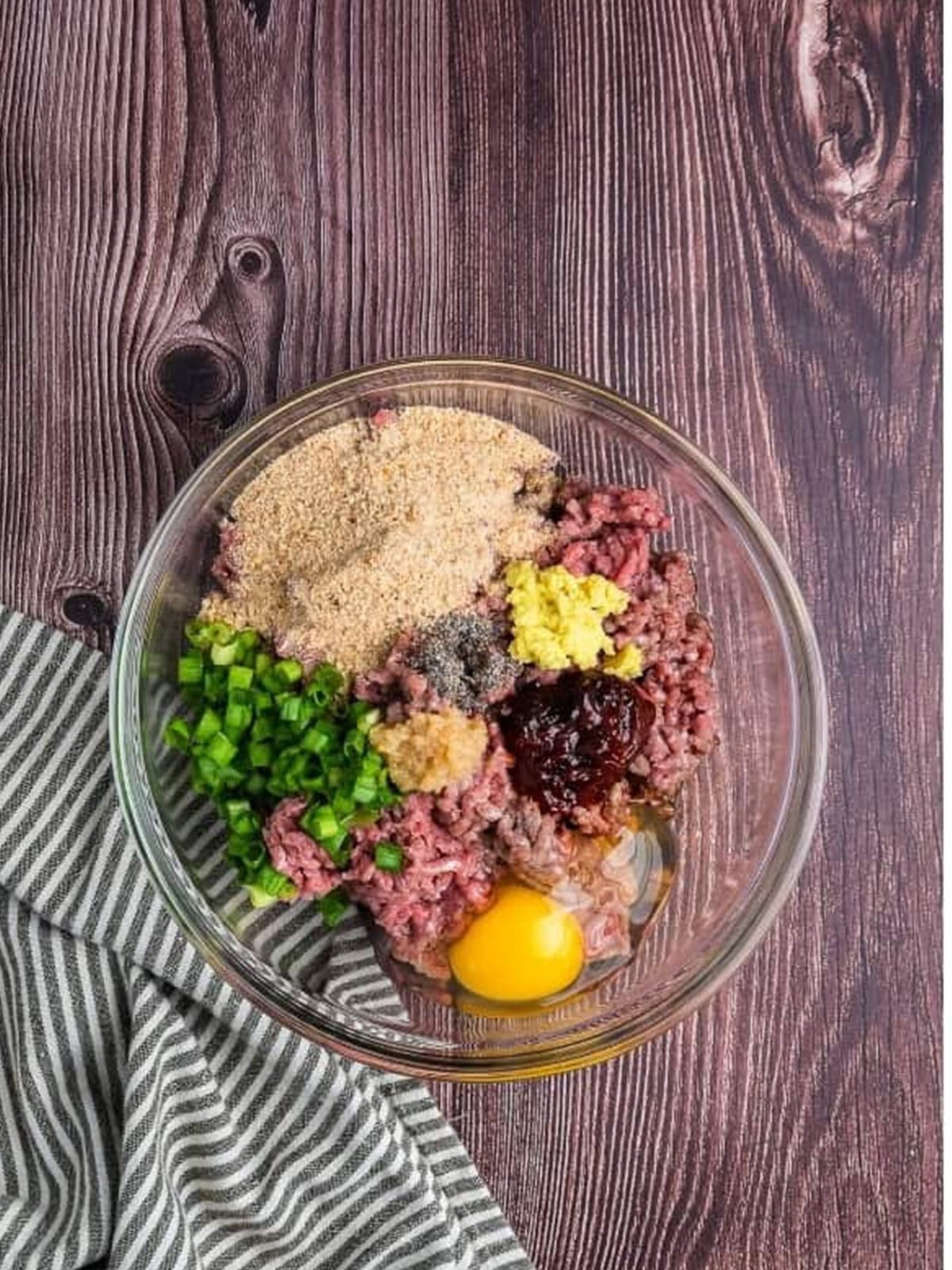 Ground beef and seasonings for Asian meatballs in a glass bowl before mixing.