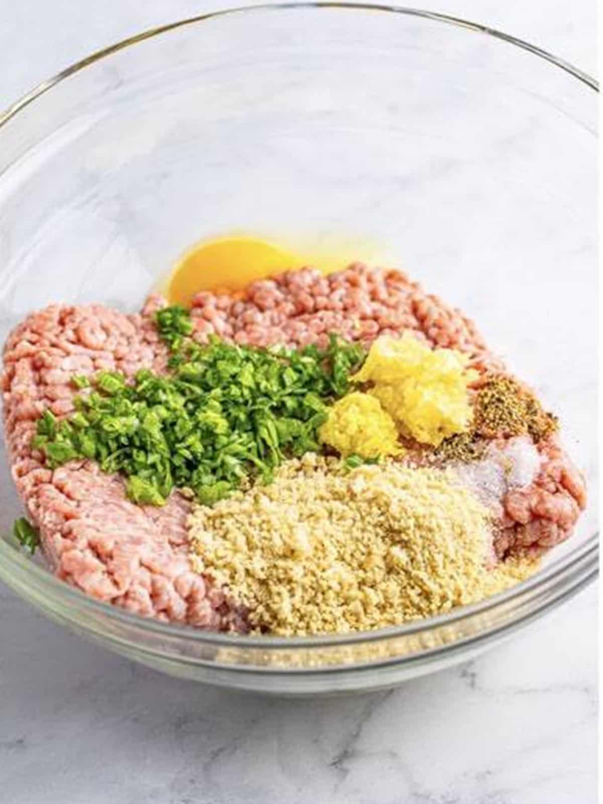 Ground pork, panko, egg, ginger, and scallions in a bowl.