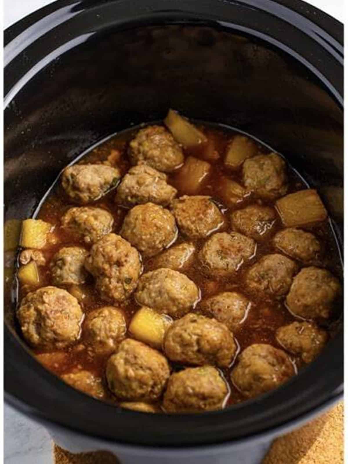 Asian pork meatballs simmering in sauce in the slow cooker.