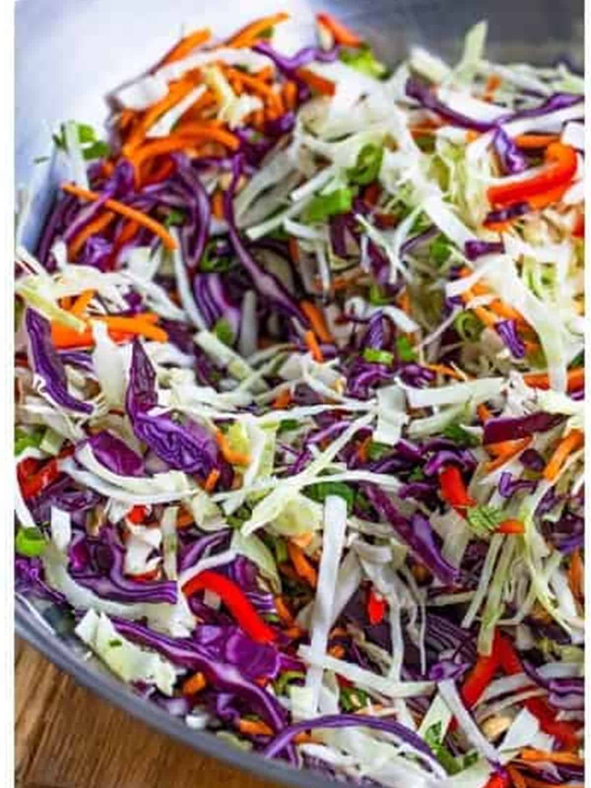 The slaw vegetables tossed together in a large bowl.