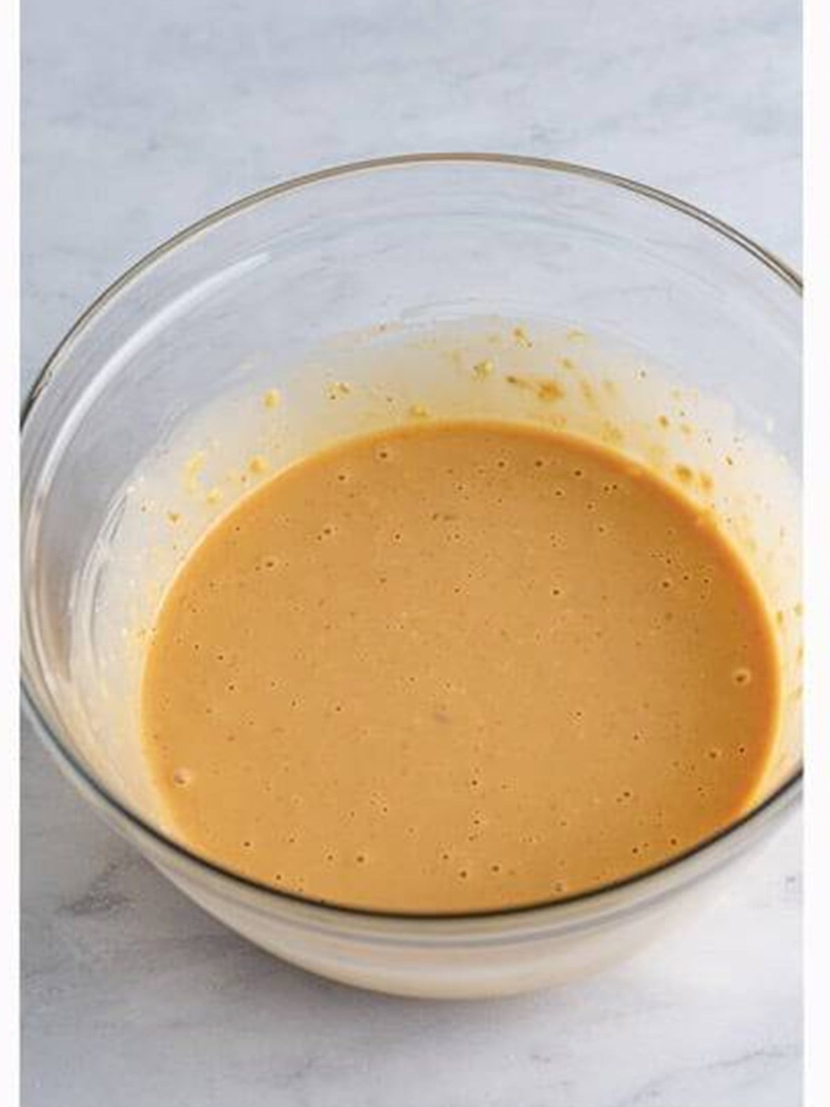 Whisked creamy Asian slaw dressing in a glass bowl.