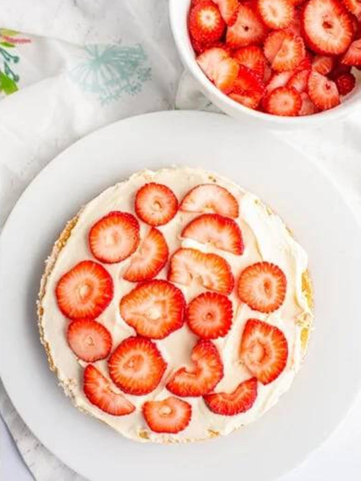 Sliced strawberries arranged over a frosted cake layer.