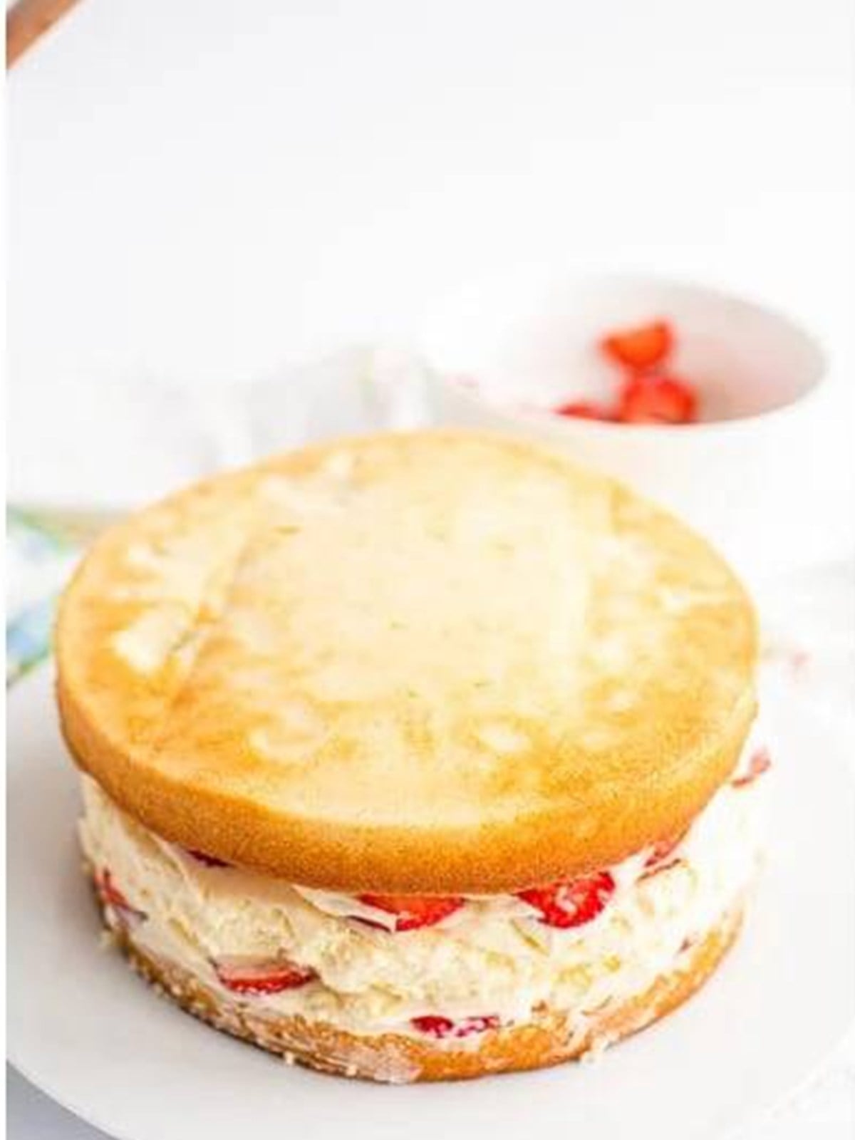 Stacking the cake and cheesecake layers with frosting and strawberries.