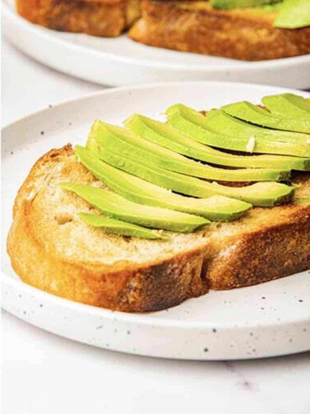 Thinly sliced avocado layered on top of toasted bread.