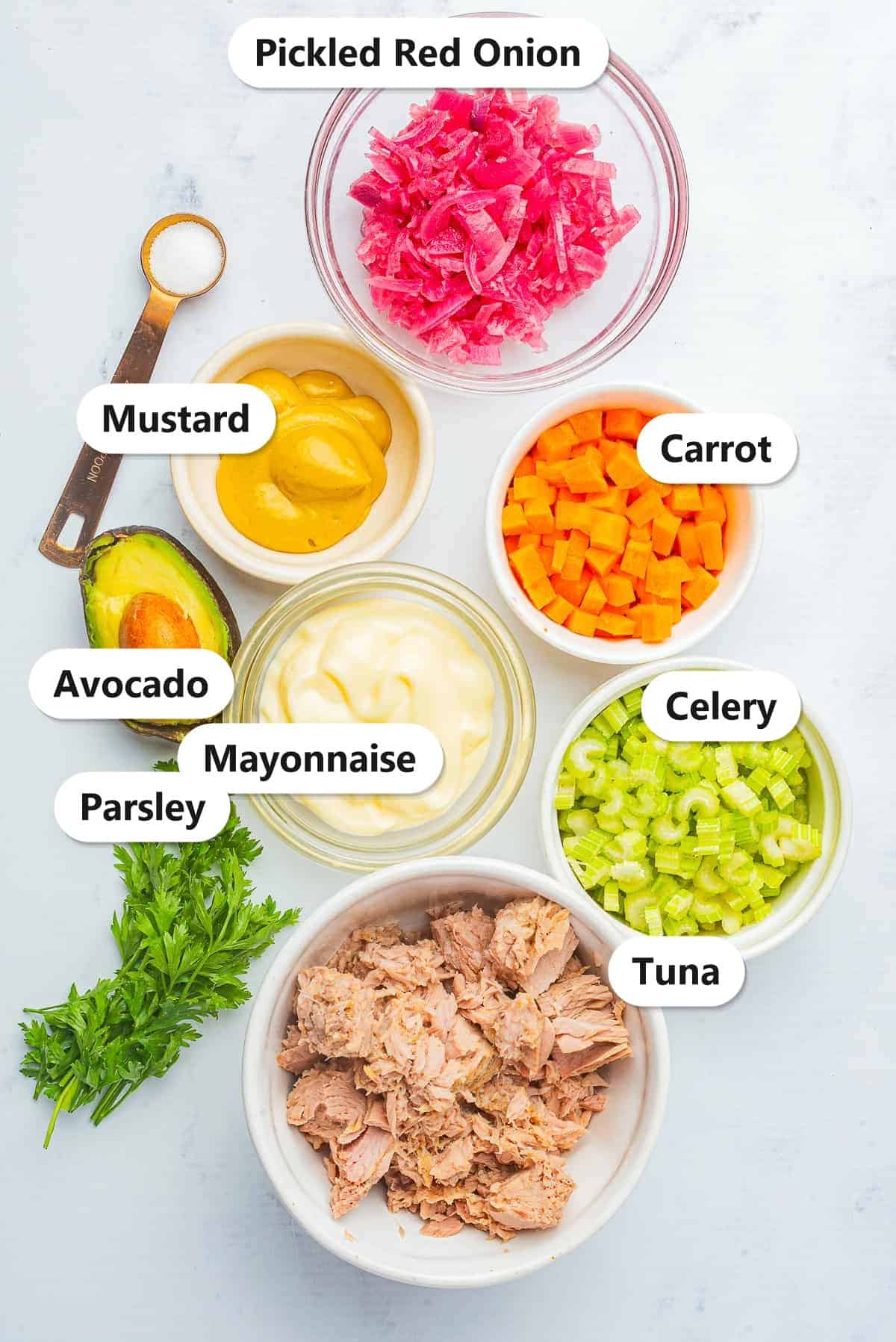 Labeled ingredients for Avocado Tuna Salad including tuna, celery, carrot, pickled red onion, avocado, parsley, mayonnaise, and mustard.