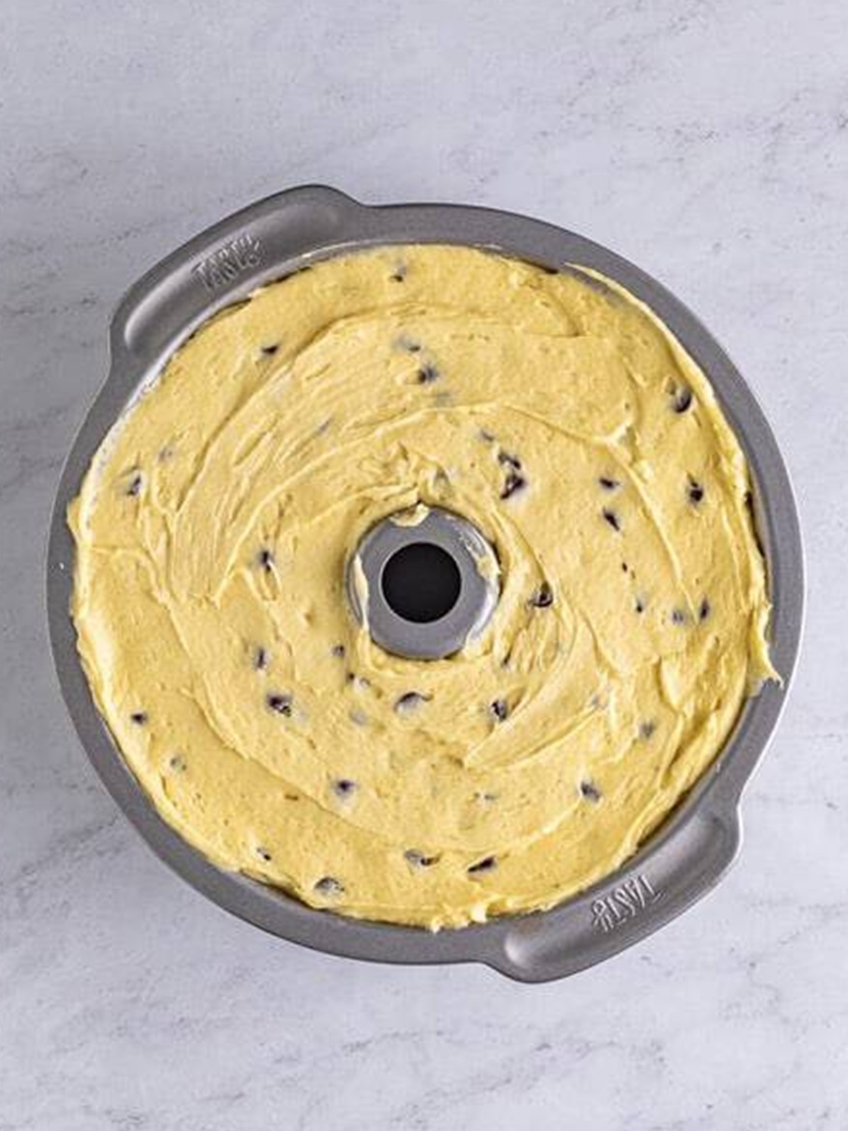 Chocolate chip pound cake batter spread in a bundt pan.
