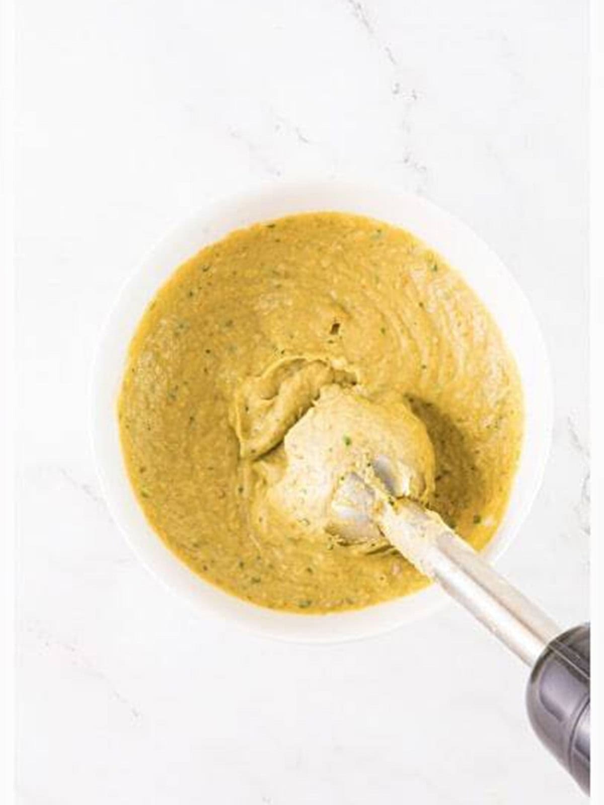 Baba ganoush being blended smooth with an immersion blender.