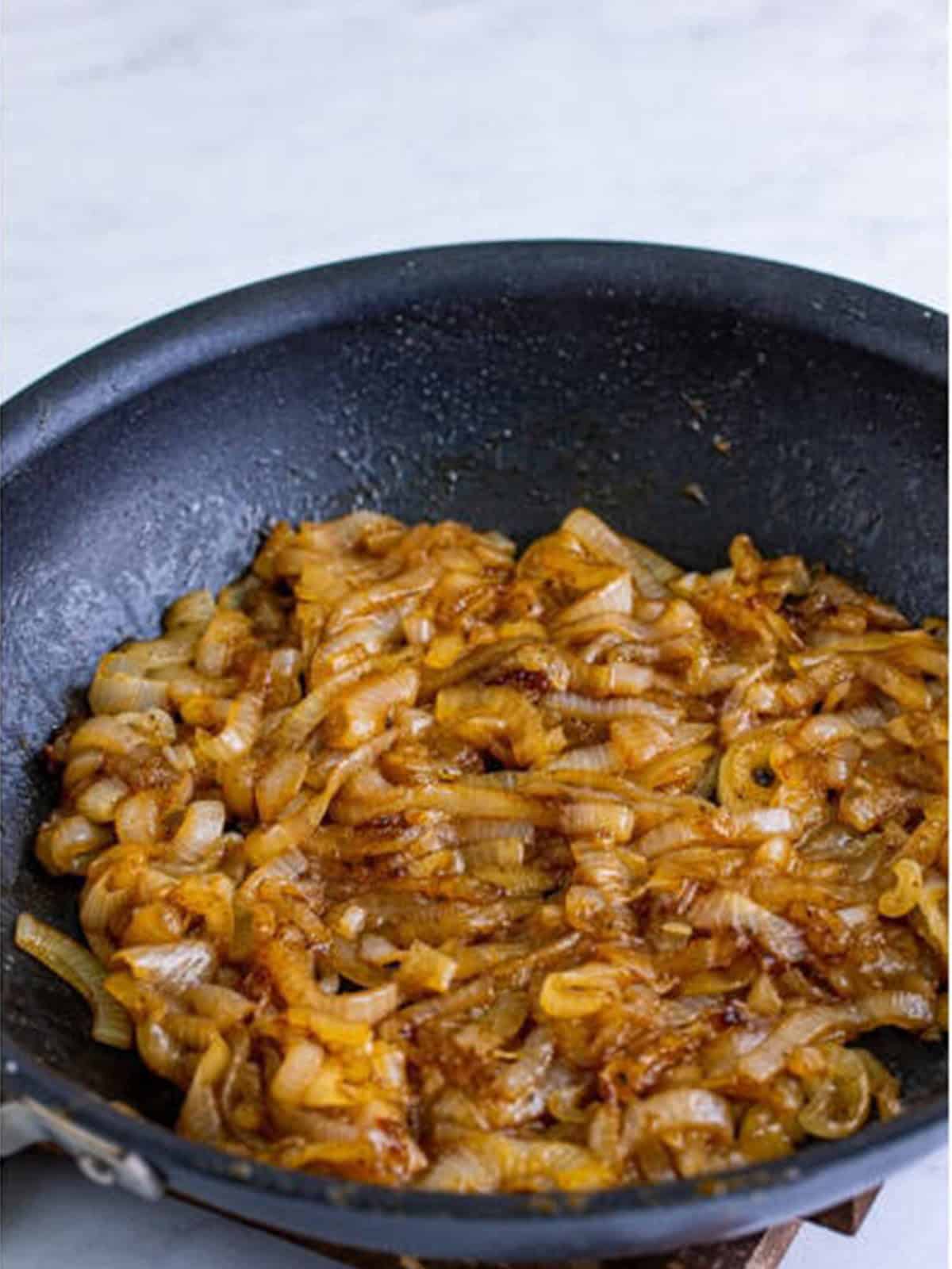 Caramelized Coca-Cola onions cooked down in a skillet.