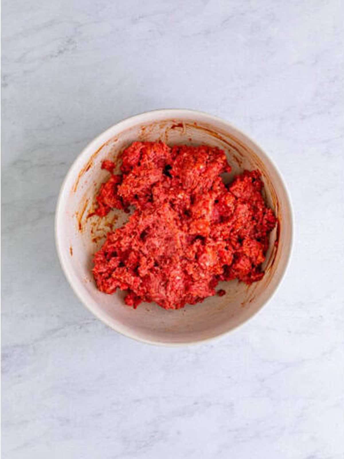 Ground beef mixed with bbq sauce and seasonings in a bowl.
