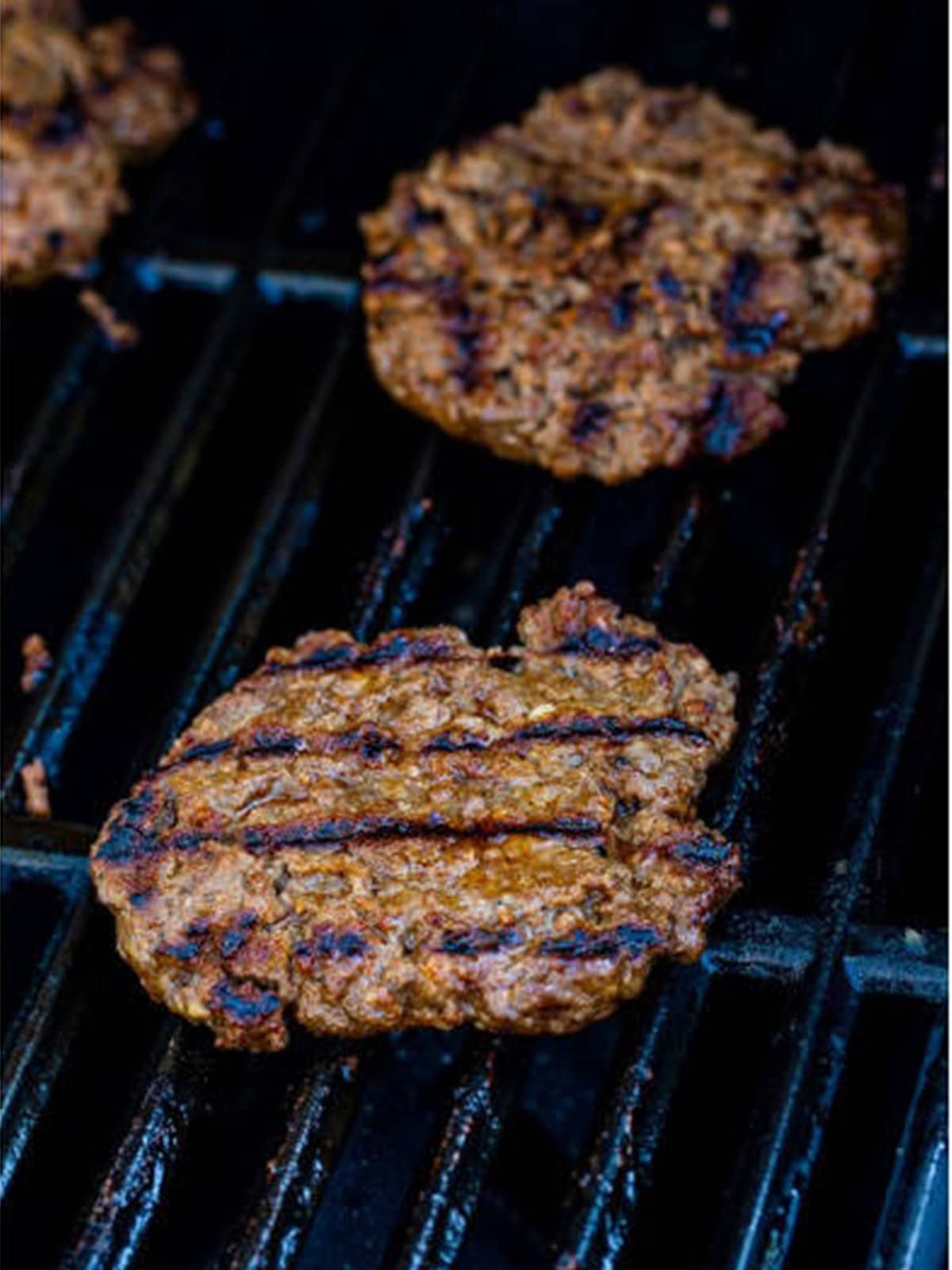 Burger patties cooking on a hot grill.