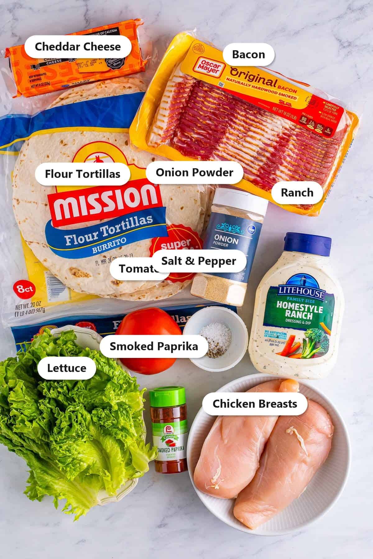 Ingredients for bacon ranch chicken wraps including chicken breasts, bacon, ranch, tortillas, cheddar, lettuce, tomato, and seasonings.
