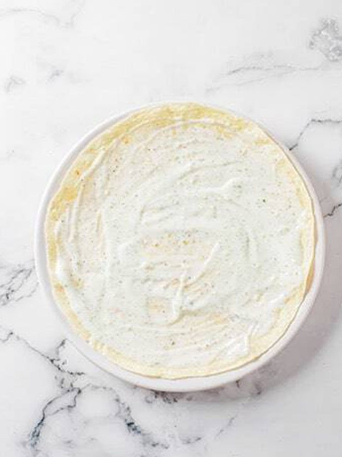 Ranch dressing spread over a flour tortilla.