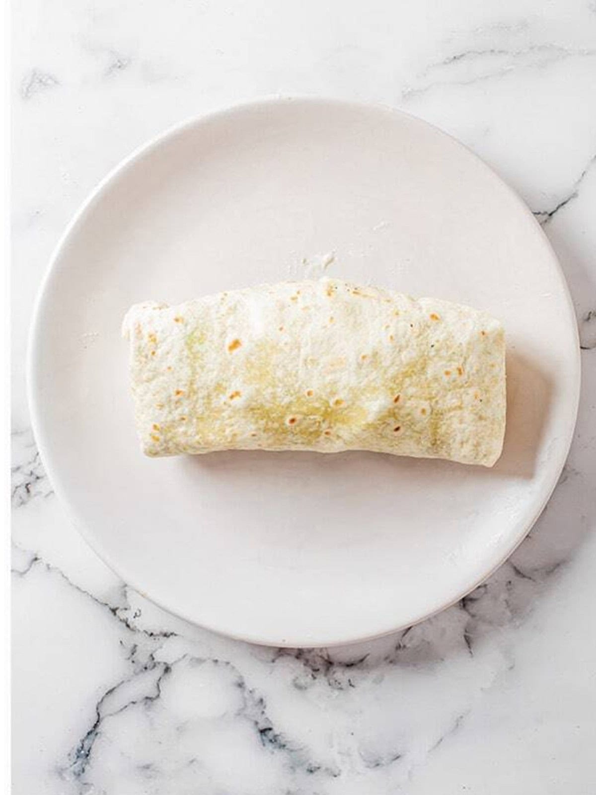 A bacon ranch chicken wrap rolled up and sliced in half.