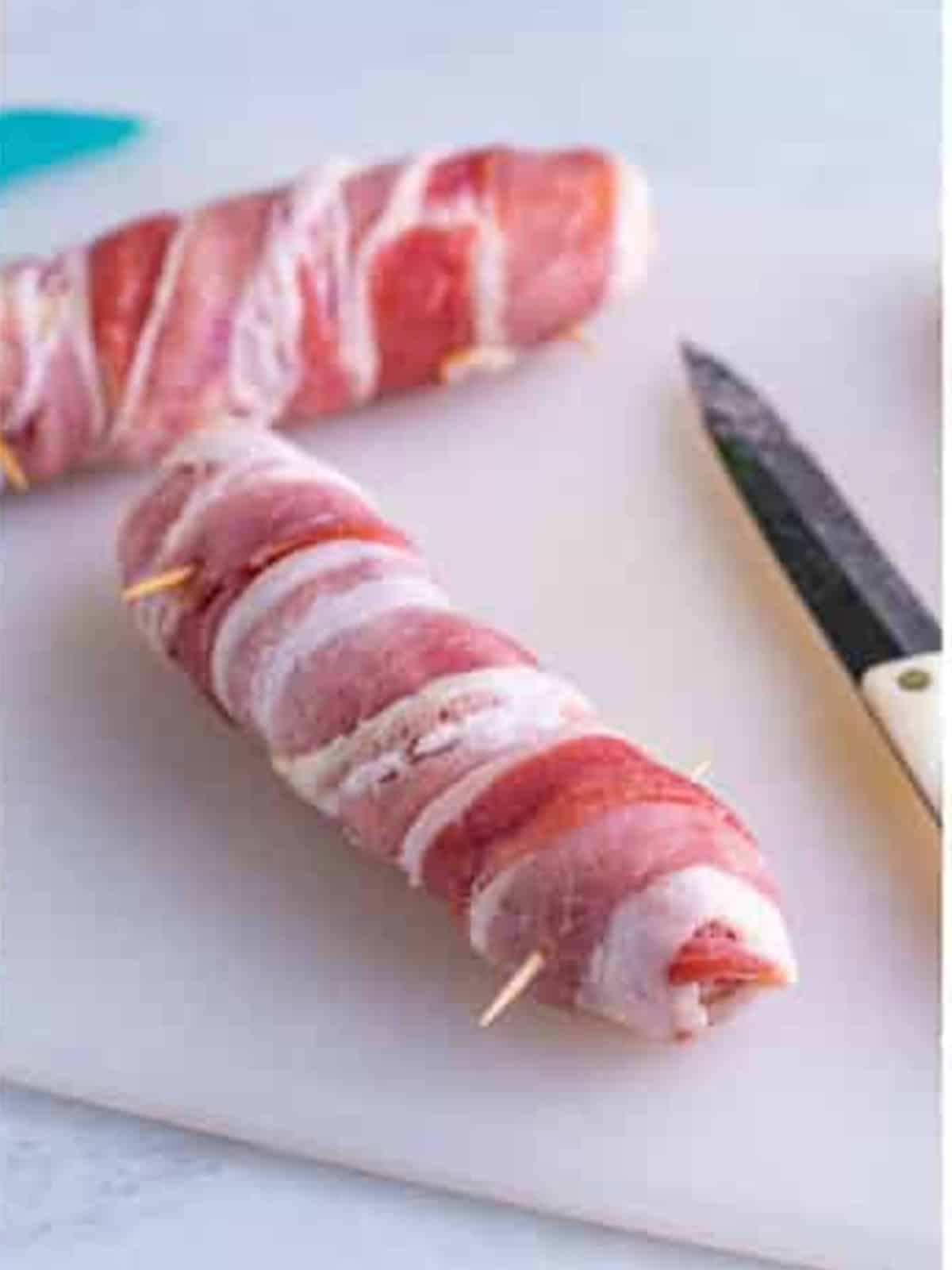 A cheese stuffed bratwurst wrapped in bacon with toothpicks.