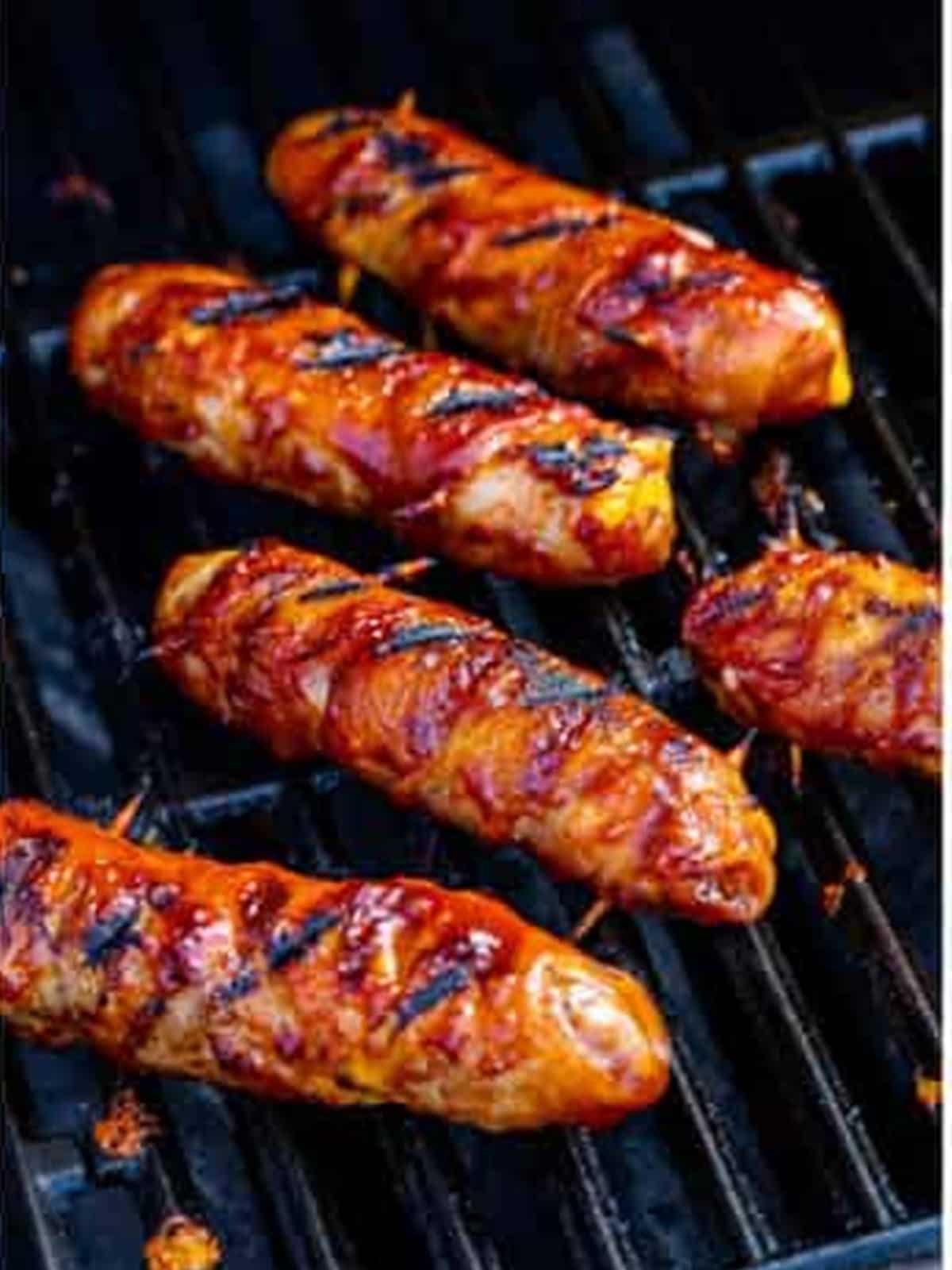 Caramelized bacon wrapped brats finished on the grill.