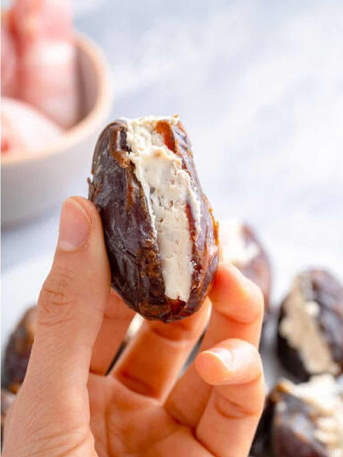 A pitted Medjool date being filled with the cream cheese and walnut mixture.