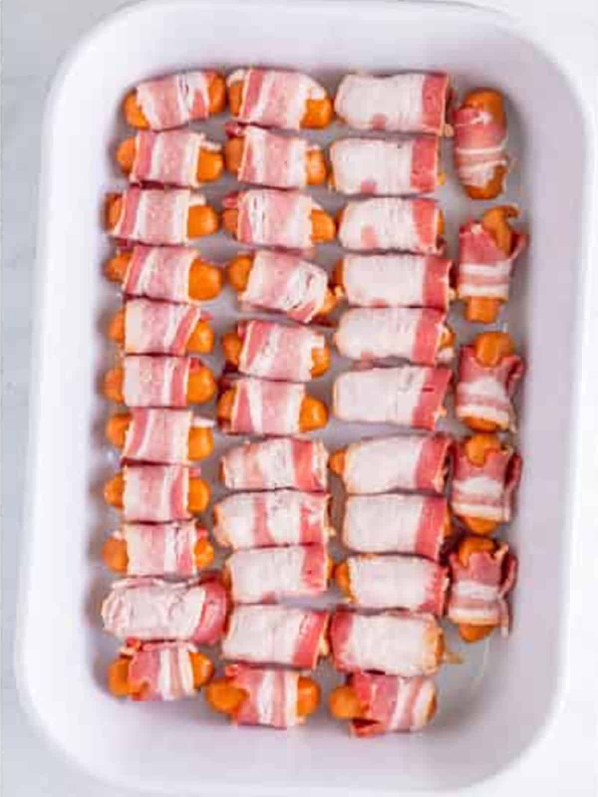 Little smokies wrapped in bacon and arranged seam side down in a baking dish.