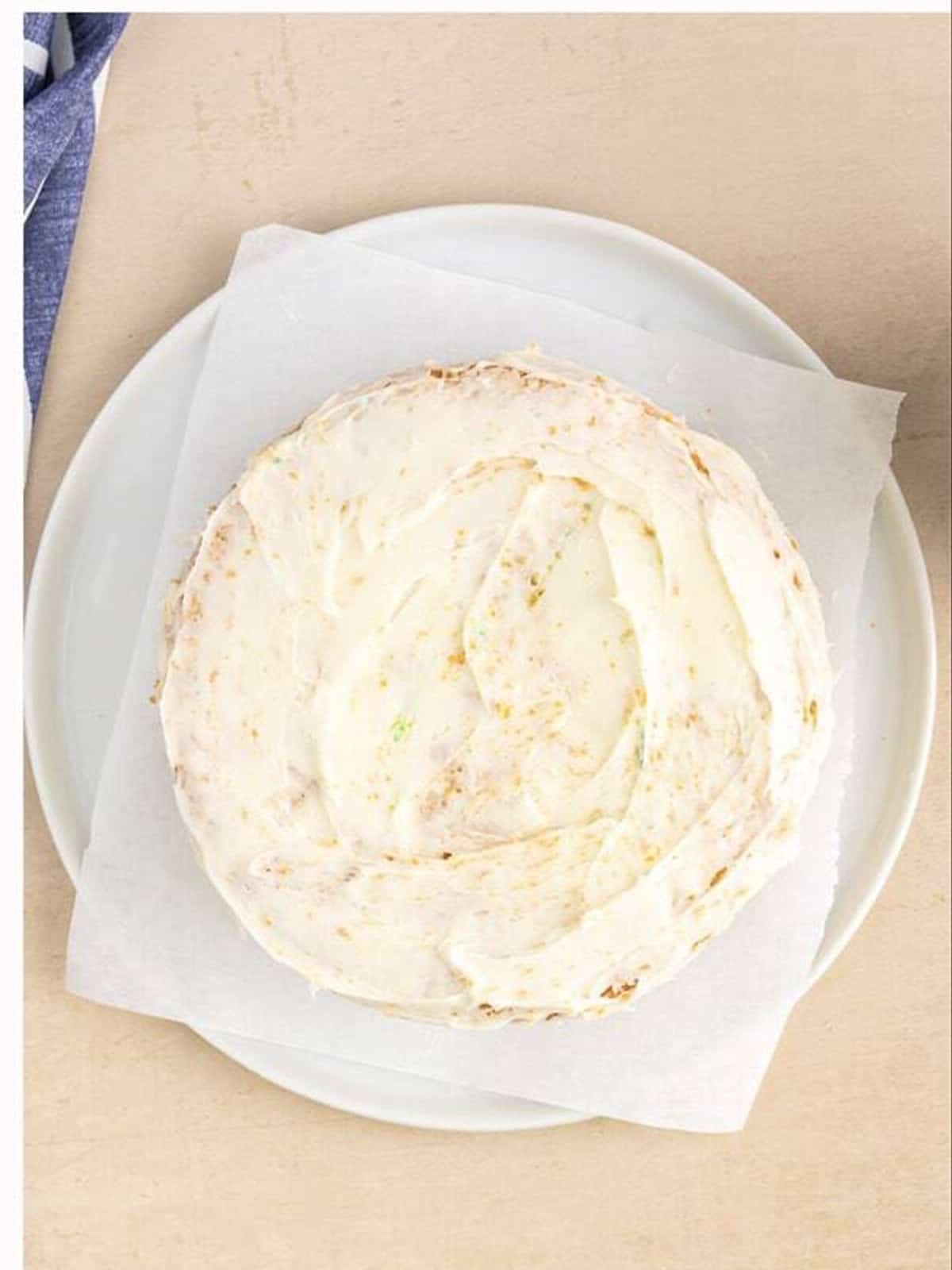 Stacked cake layers covered in a thin crumb coat of frosting.
