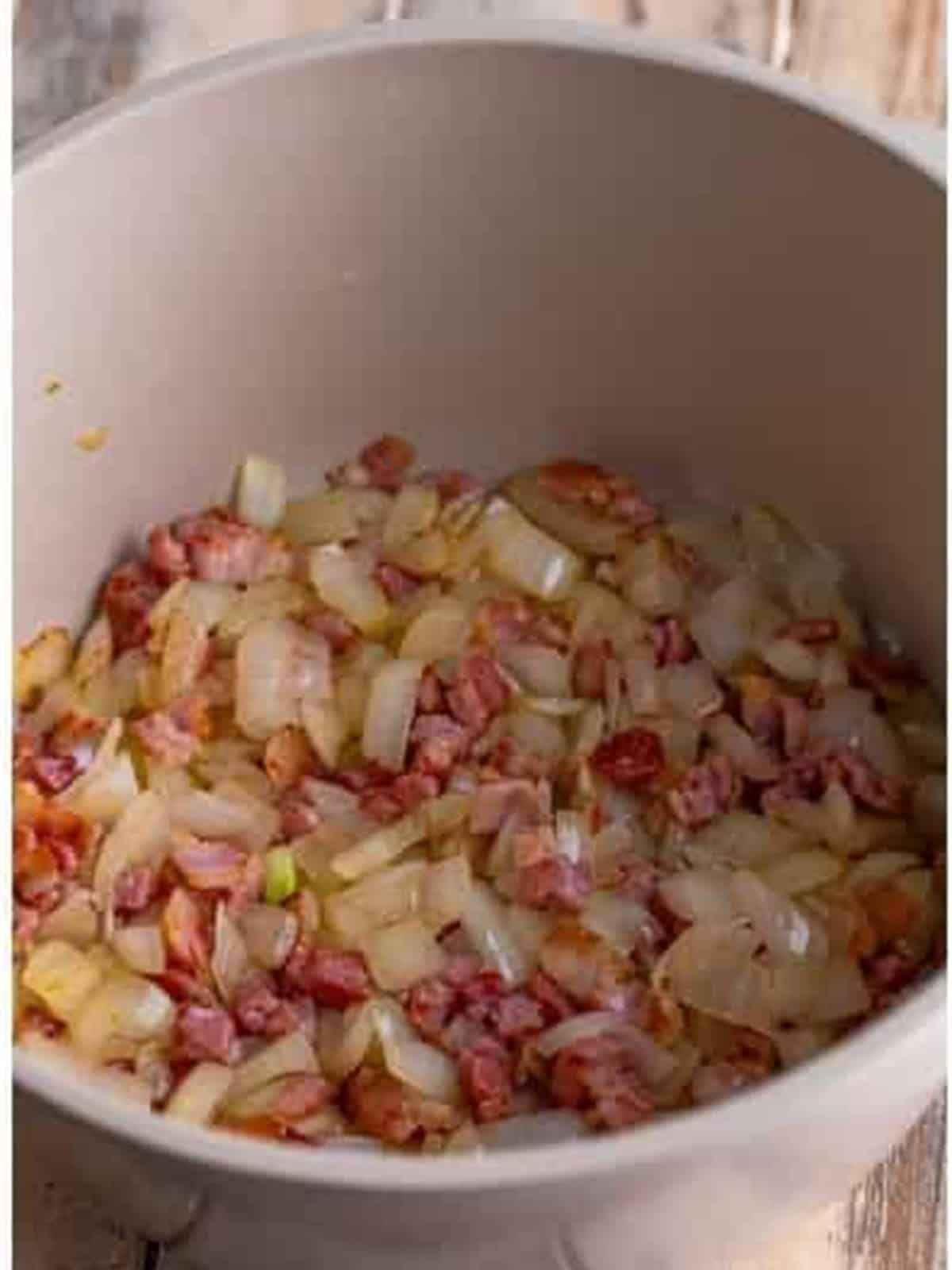 Diced sweet onion added to the rendered salt pork in a pot.