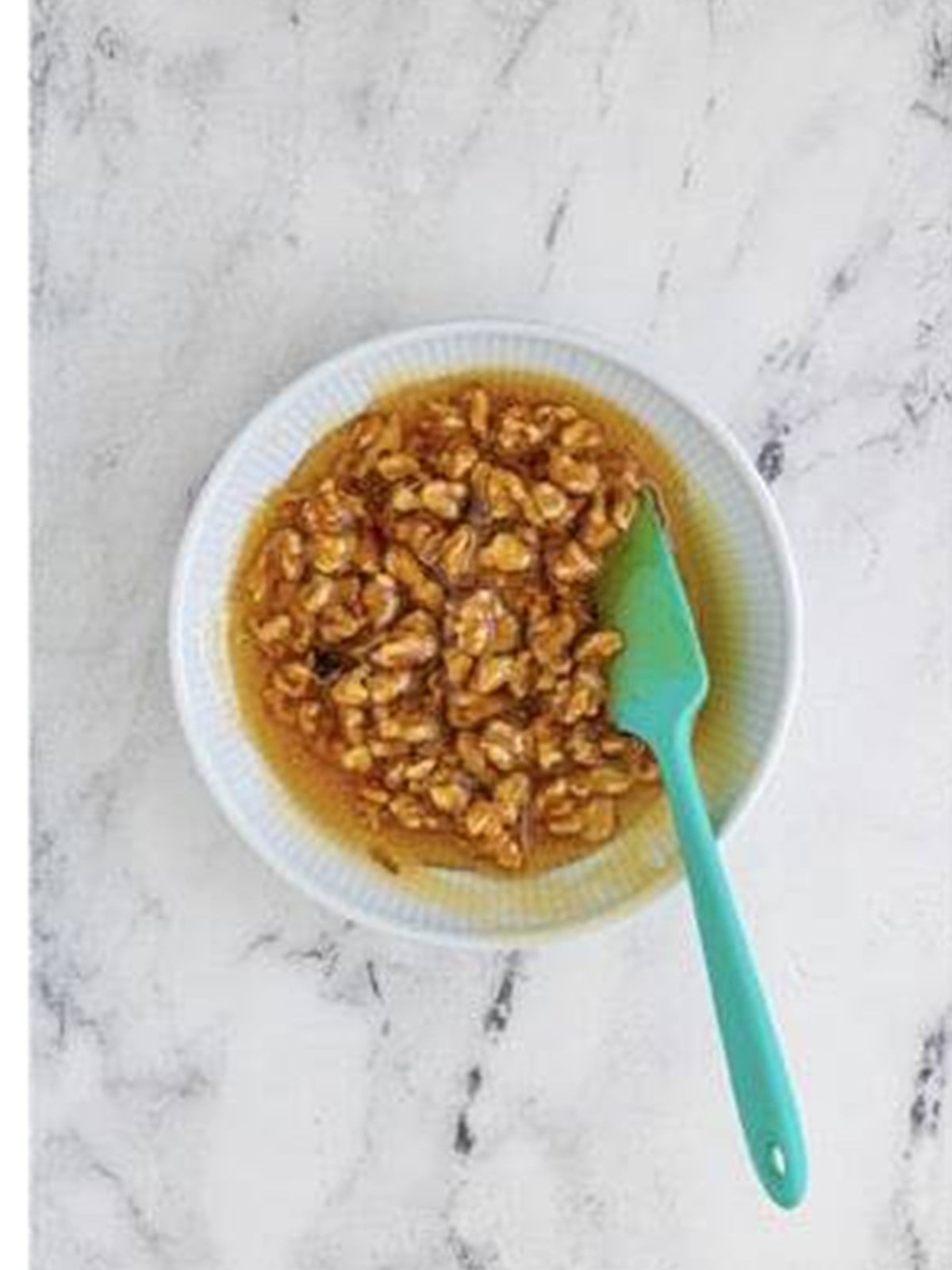 Honey and chopped walnuts stirred together in a small bowl for baked brie.