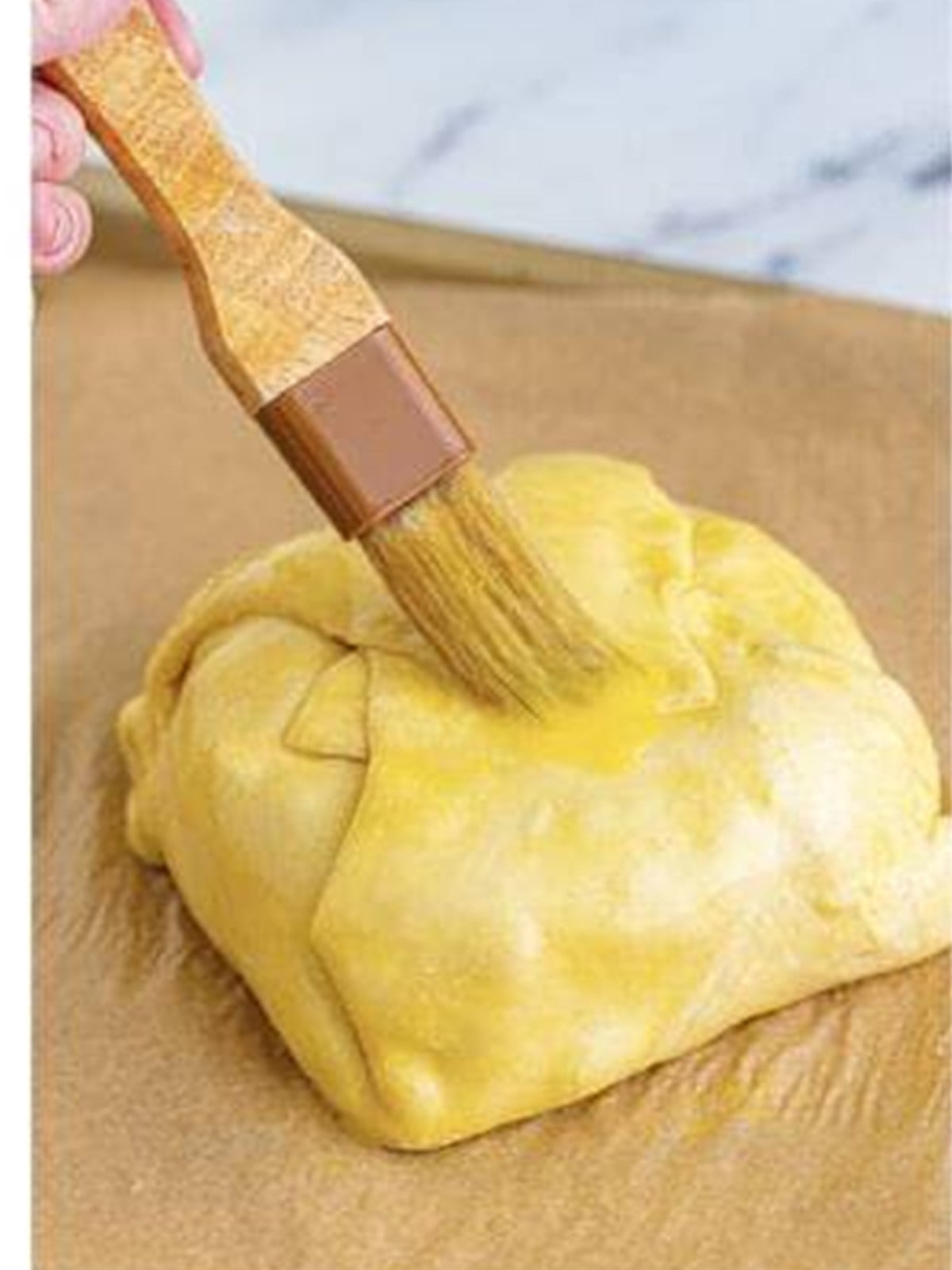 Puff pastry wrapped brie brushed with egg wash before baking.